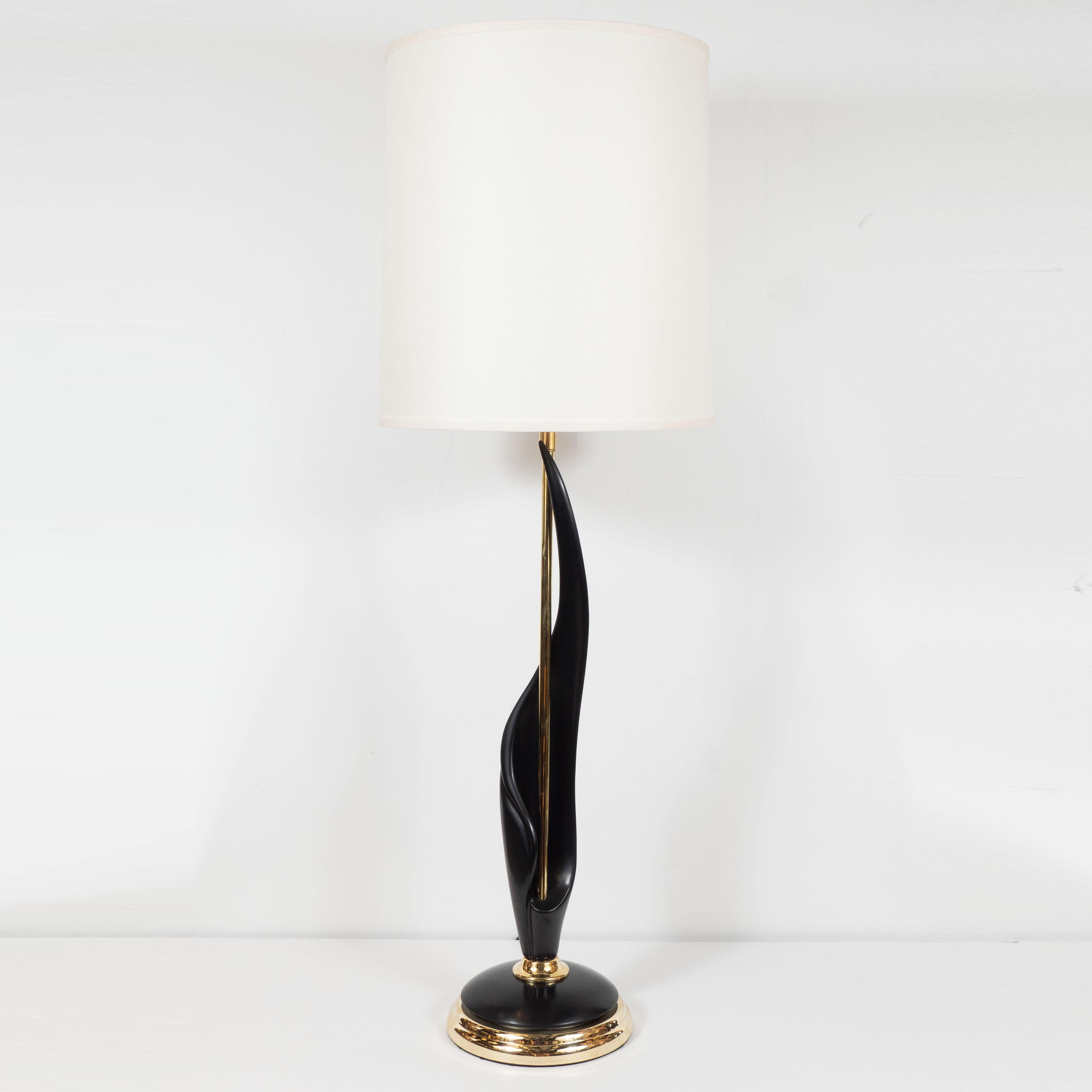 This elegant and dramatic pair of Mid-Century Modern table lamps was realized in the United States, circa 1970. They feature a domed base in alternating layers of lustrous brass and ebonized walnut from which a cylindrical brass rod ascends. A