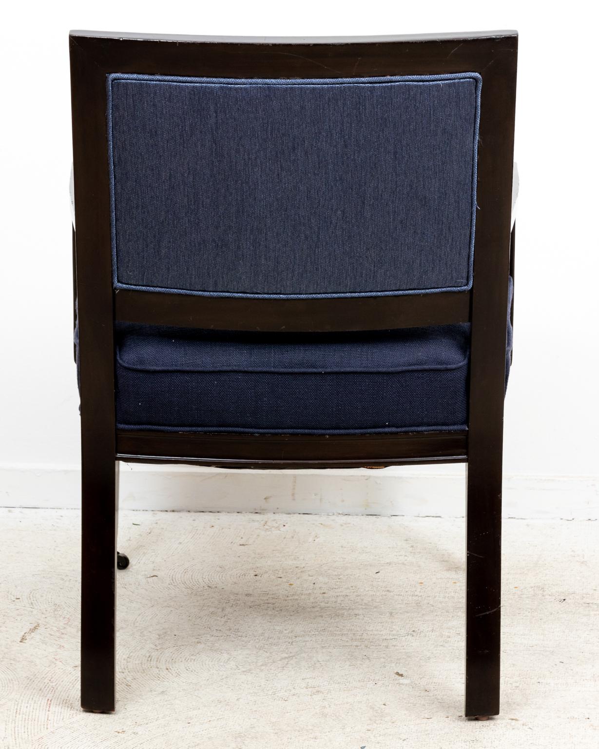 Circa 1970s pair of Mid-Century Modern square back Mahogany armchairs with dark blue upholstery and brushed brass castors. Made in the United States. Please note of wear consistent with age.