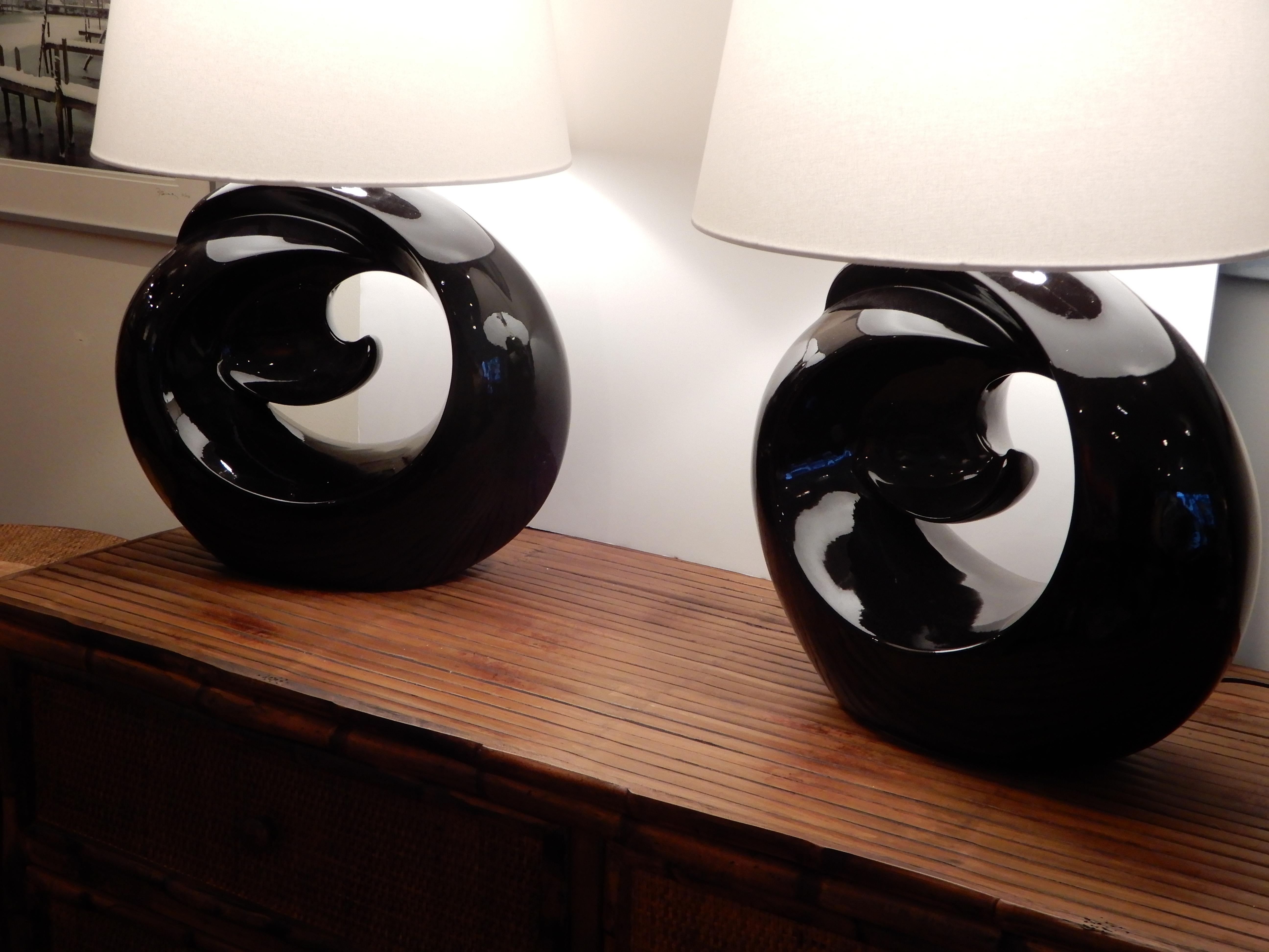 A striking pair of Mid-Century Modern black ceramic lamps and a rare find in these dramatic black wave lamps, three way switch, original finial's, the lamp measures 18 inches from the base to the socket and 27 inches from the base to the the top of
