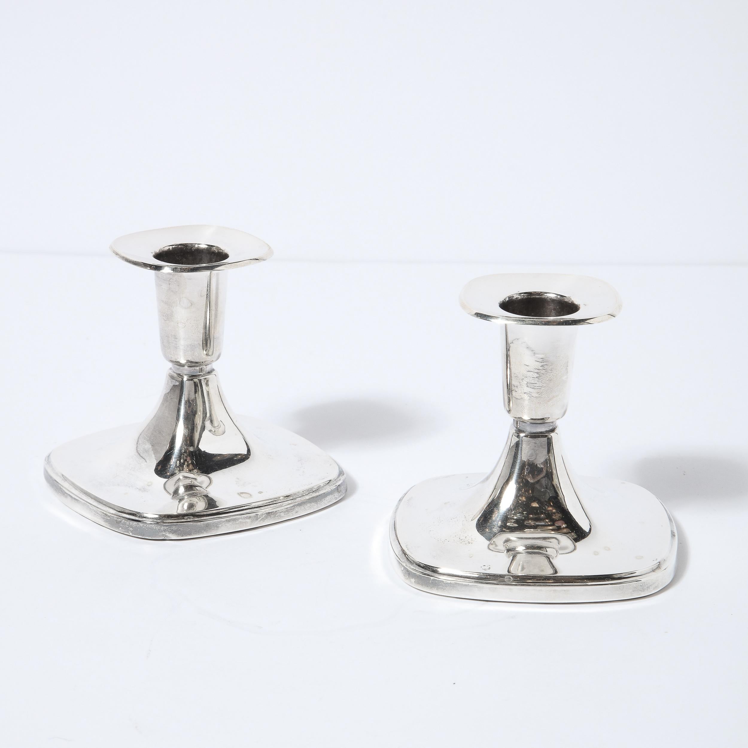 This refined pair of Mid-Century Modern candlesticks were realized in the United States, circa 1960. They feature four sided bases with rounded corners that taper upwards to a bobeche of the same form- all in lustrous sterling silver. With their