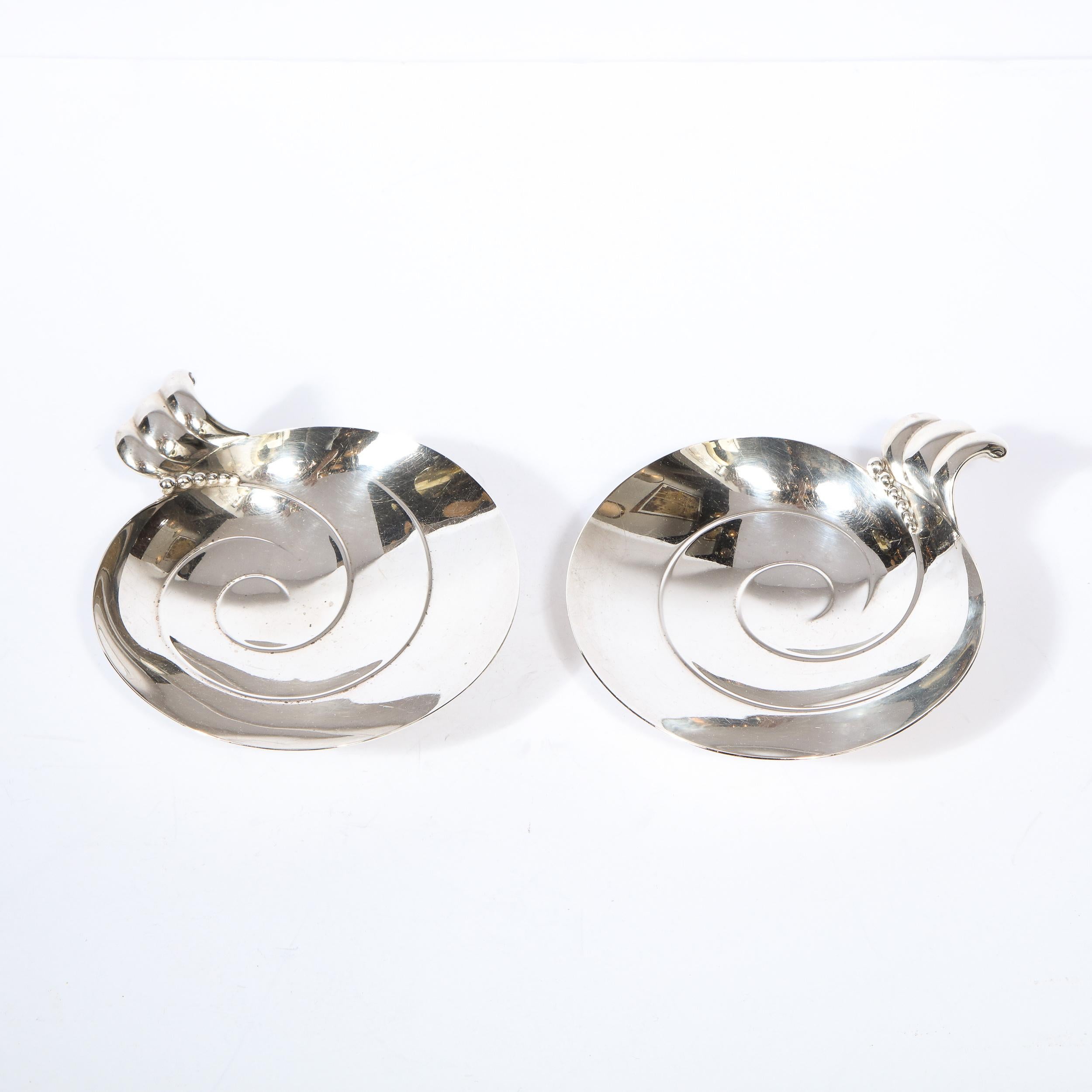 This stunning pair of footed sterling silver decorative dishes were realized by the fabled American maker Tiffany & Co. in the United States, circa 1950. They feature circular bodies with a slightly concave centers with an incised swirling pattern;