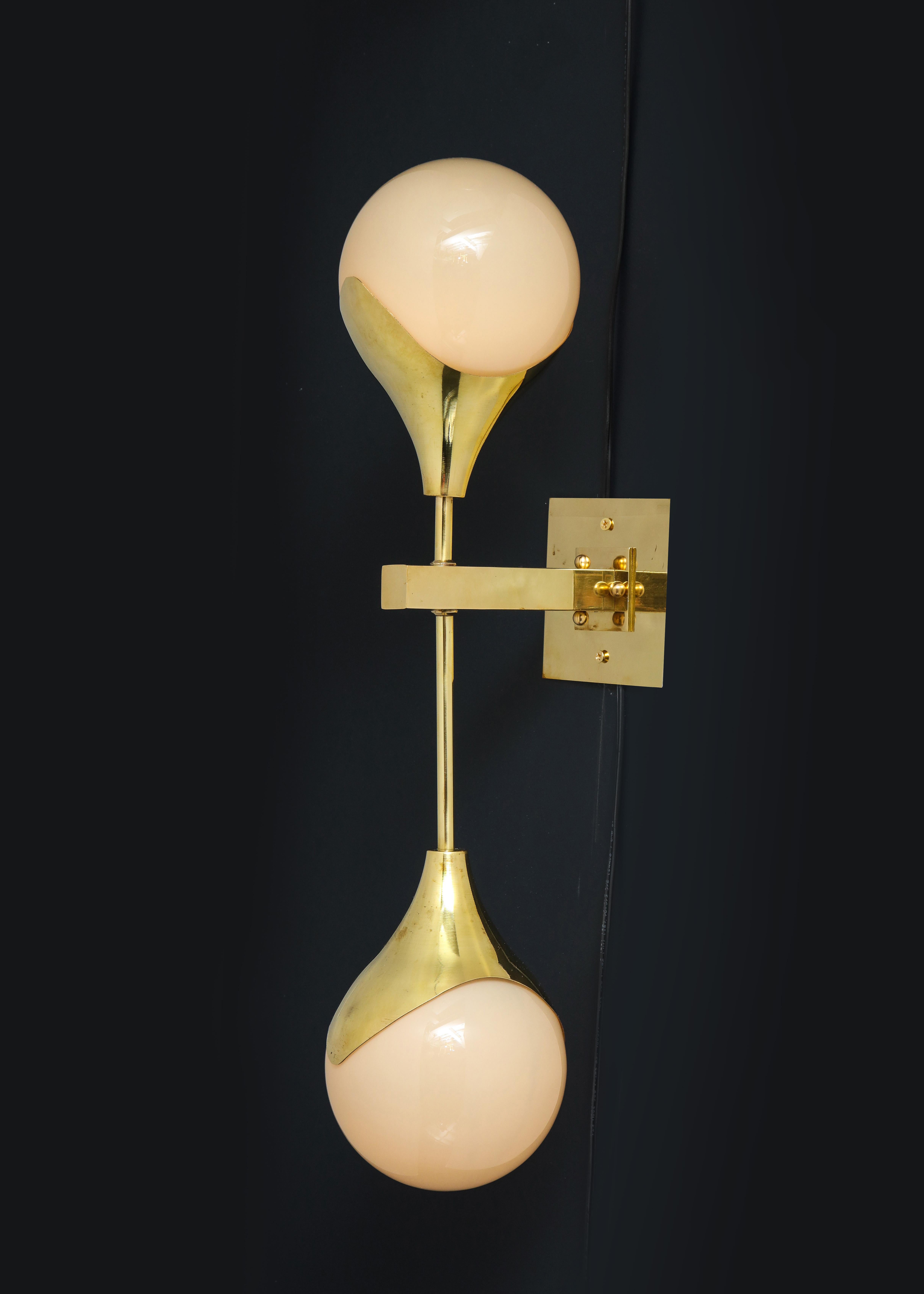 Pair of unique dumbbell-shaped brass sconces with Murano white glass globes and brass plates. Sconces can be installed with long arm up or down (your preference). Wired for U.S. standards. Each light holds two candelabra-base bulbs. This pair of