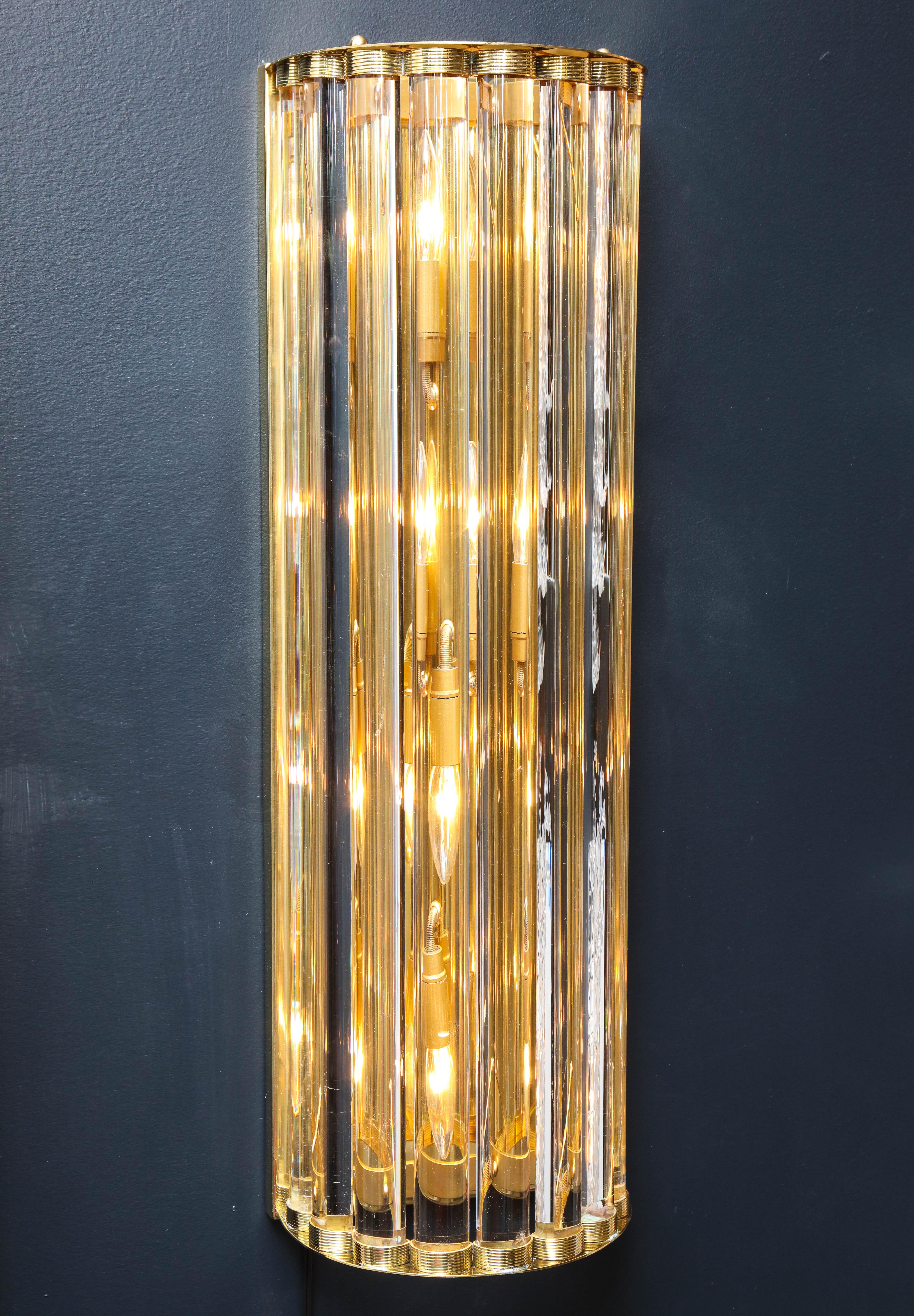 This pair of large Italian handcrafted sconces consist of solid Murano clear glass rods held between two curved solid brass frame structures.  The brass reflects behind the clear round prisms, casting a decadent gold hue. Heavy and substantial.