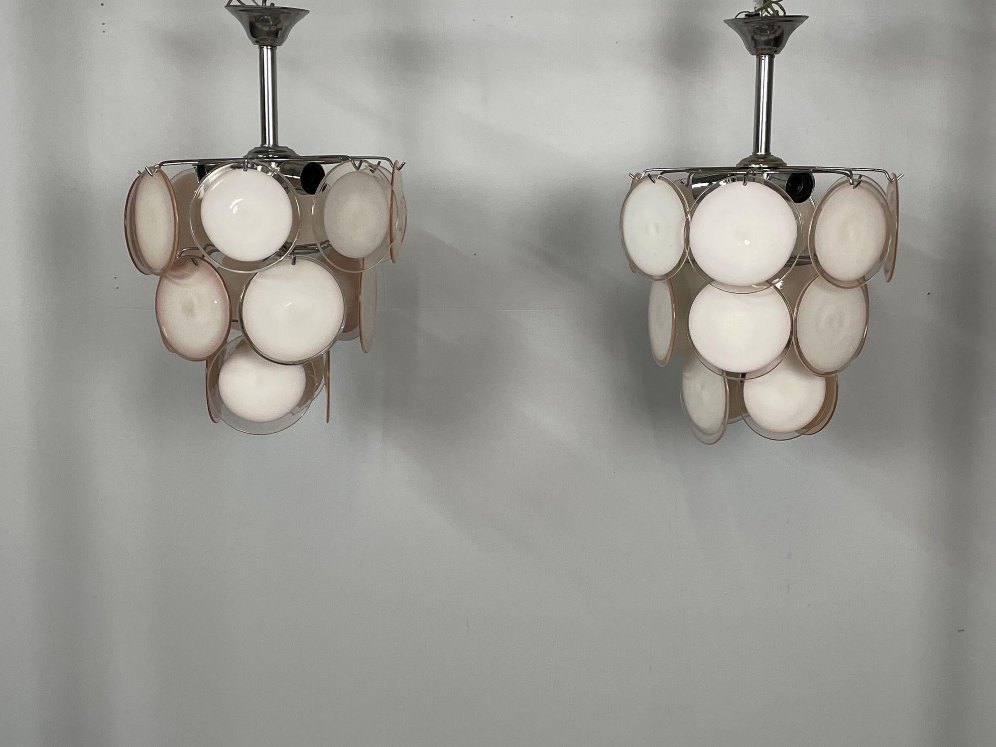 Coppia di piccoli lampadari a disco in vetro di Murano rosa in stile Mid-Century Modern.
Una coppia di lampadari in vetro di Murano della metà del secolo scorso nella classica configurazione a dischi sospesi. Ogni apparecchio è composto da 18