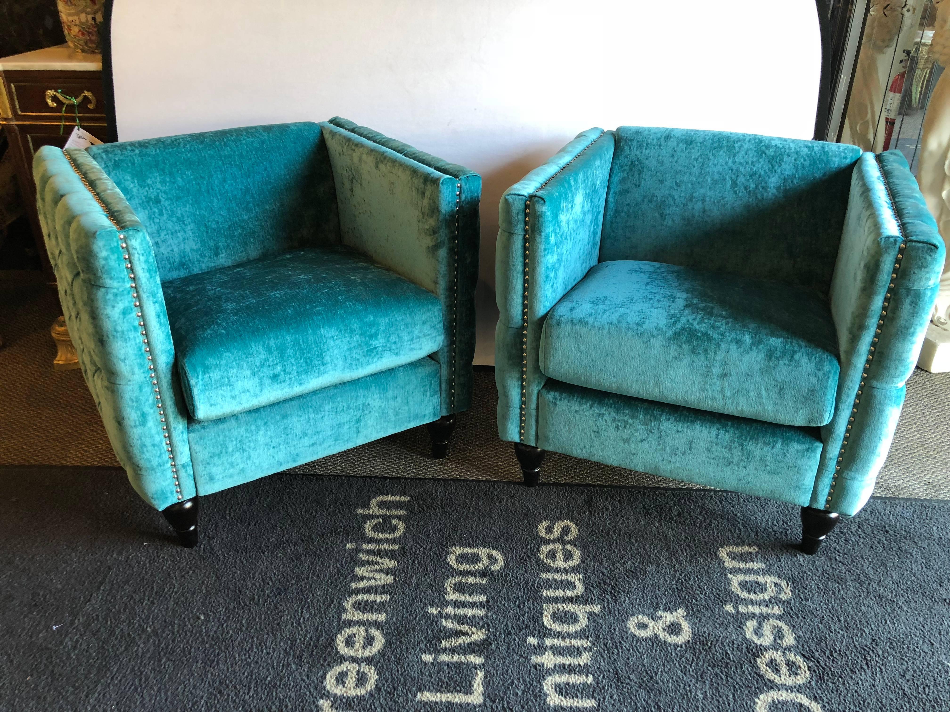 Pair of teal tufted oversized box form armchairs. Each of these finely upholstered and colorful arm chairs have tufted sides. Both sit on ebony bulbous legs and have chrome tacked sides.