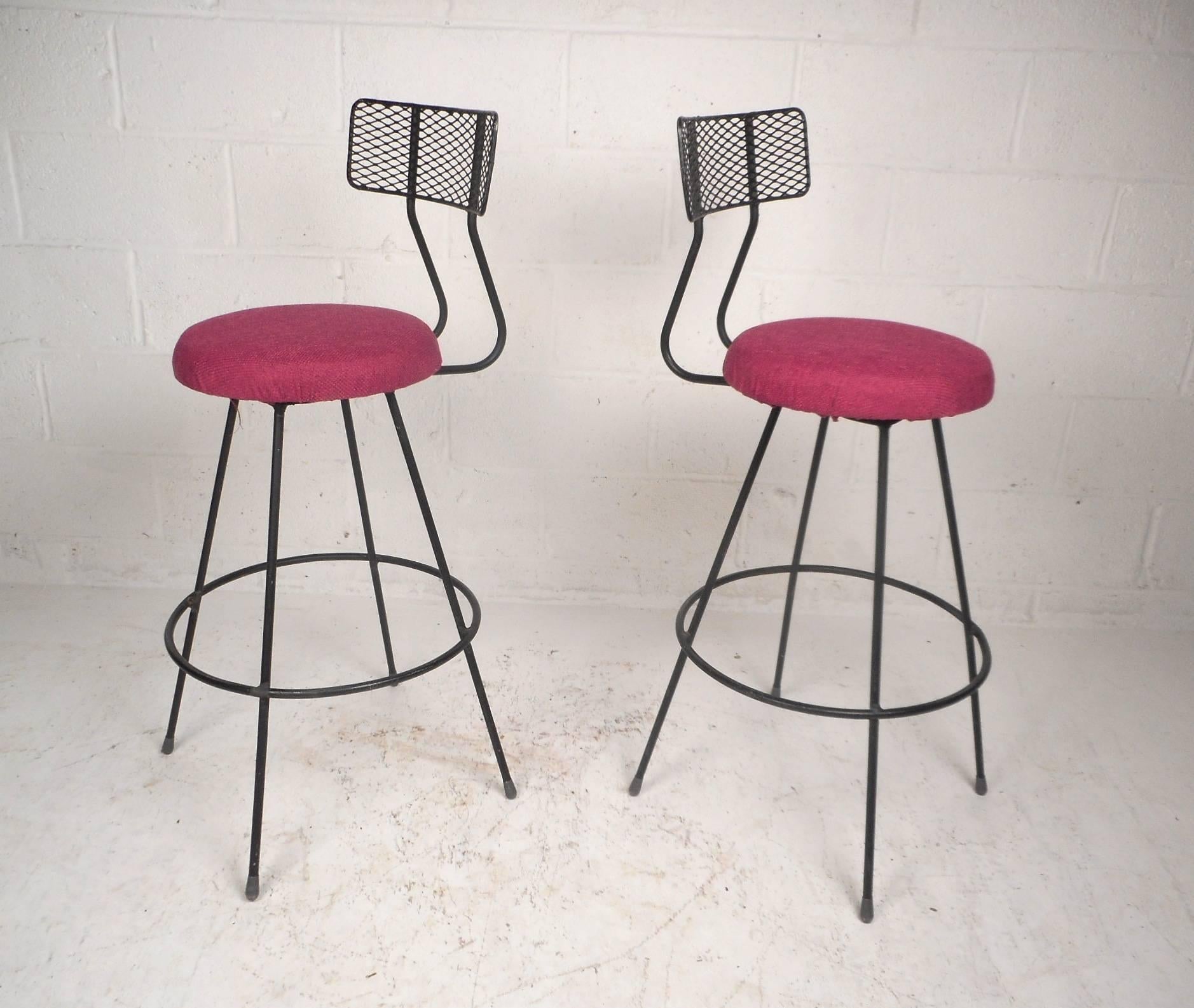Stunning pair of vintage modern bar stools with grated metal back rests and iron rod bases. Wonderful design with a conveniently placed circular kick rest and long splayed legs. Sturdy construction and elaborate colorful upholstery make this