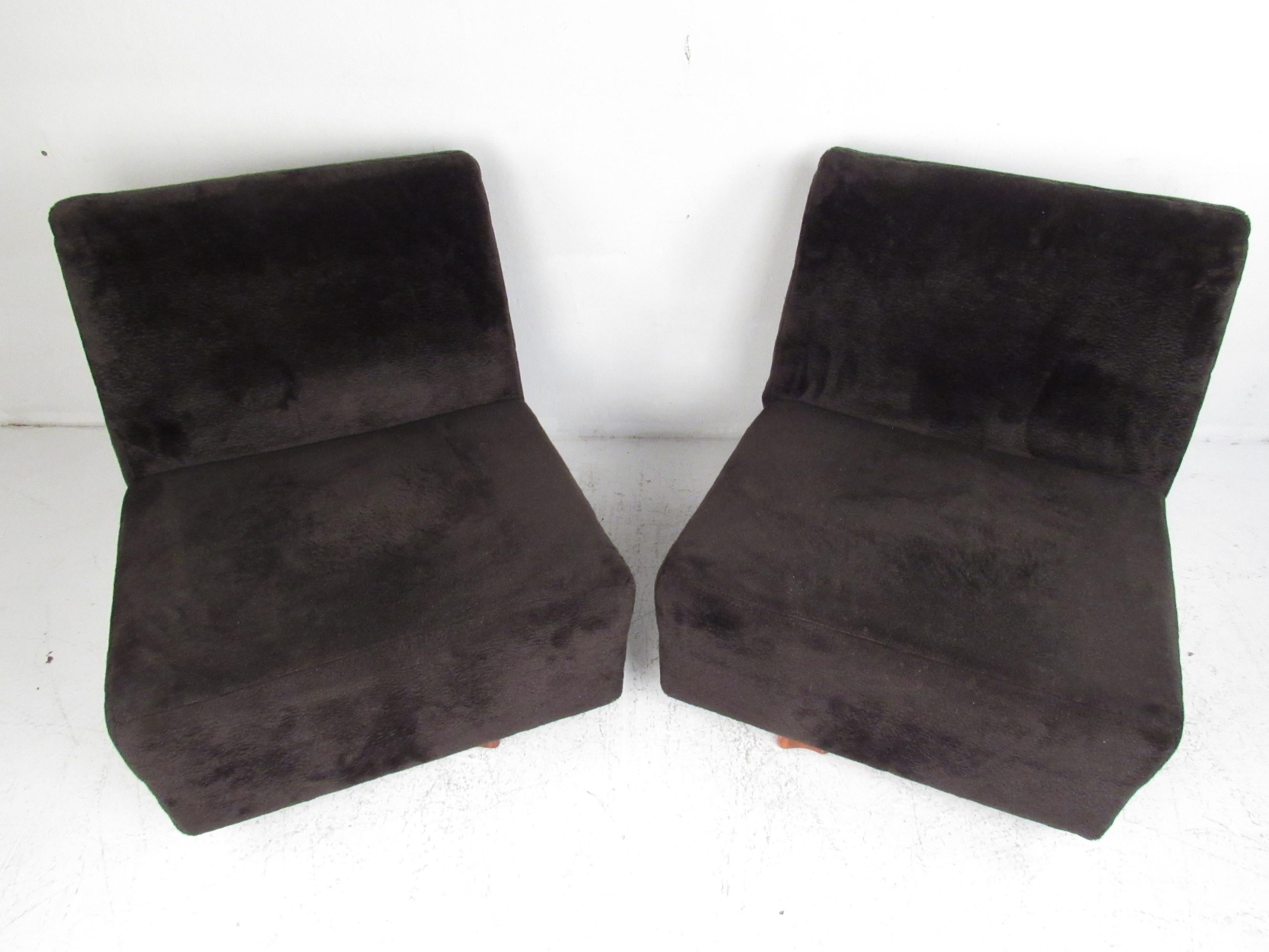 This beautiful pair of vintage modern lounge chairs feature a slipper design covered in plush black upholstery. The thick padded seating and wide design ensure maximum comfort. This pair of midcentury lounge chairs boast a brutalist style swivel