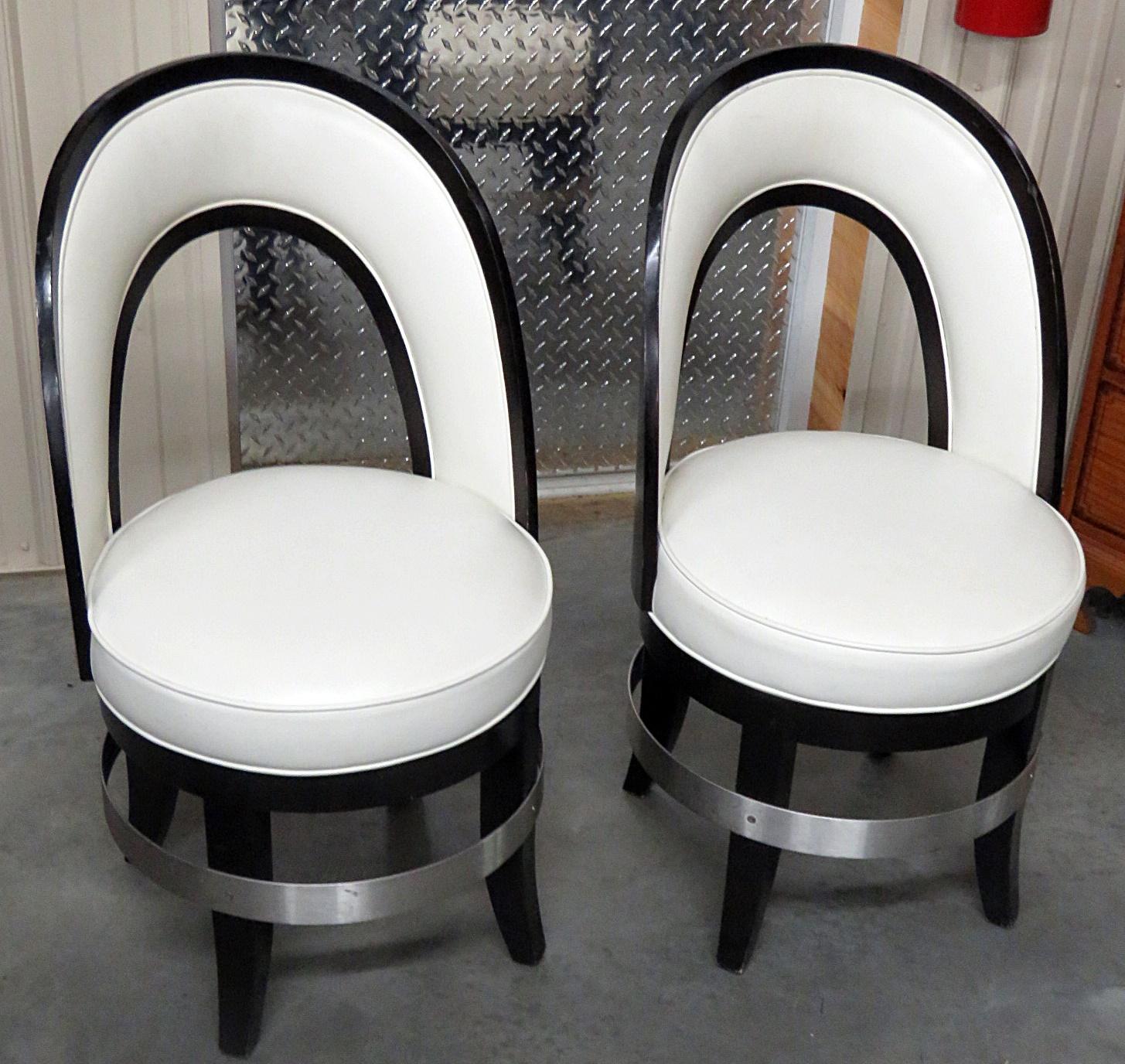 Pair of Mid-Century Modern swiveling club chairs with an ebonized frame and leather upholstery.