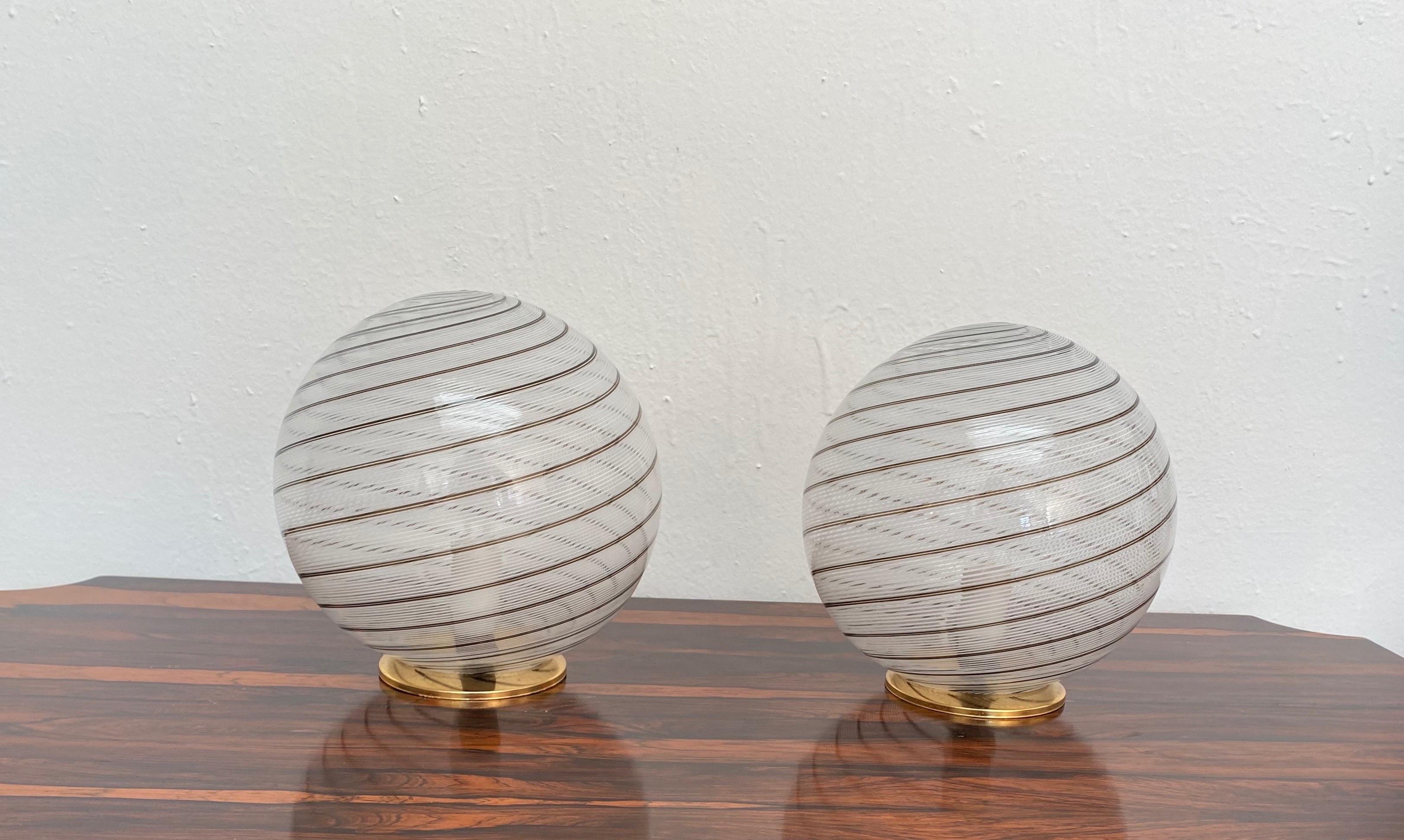 Pair of Mid-Century Modern one-light, 'Sphere' table lamps attributed to Venini, circa 1970.
Hand blown in the 'Tessuto' technique in white, clear and brown murano glass.
Each holds one E14 bulb.
    