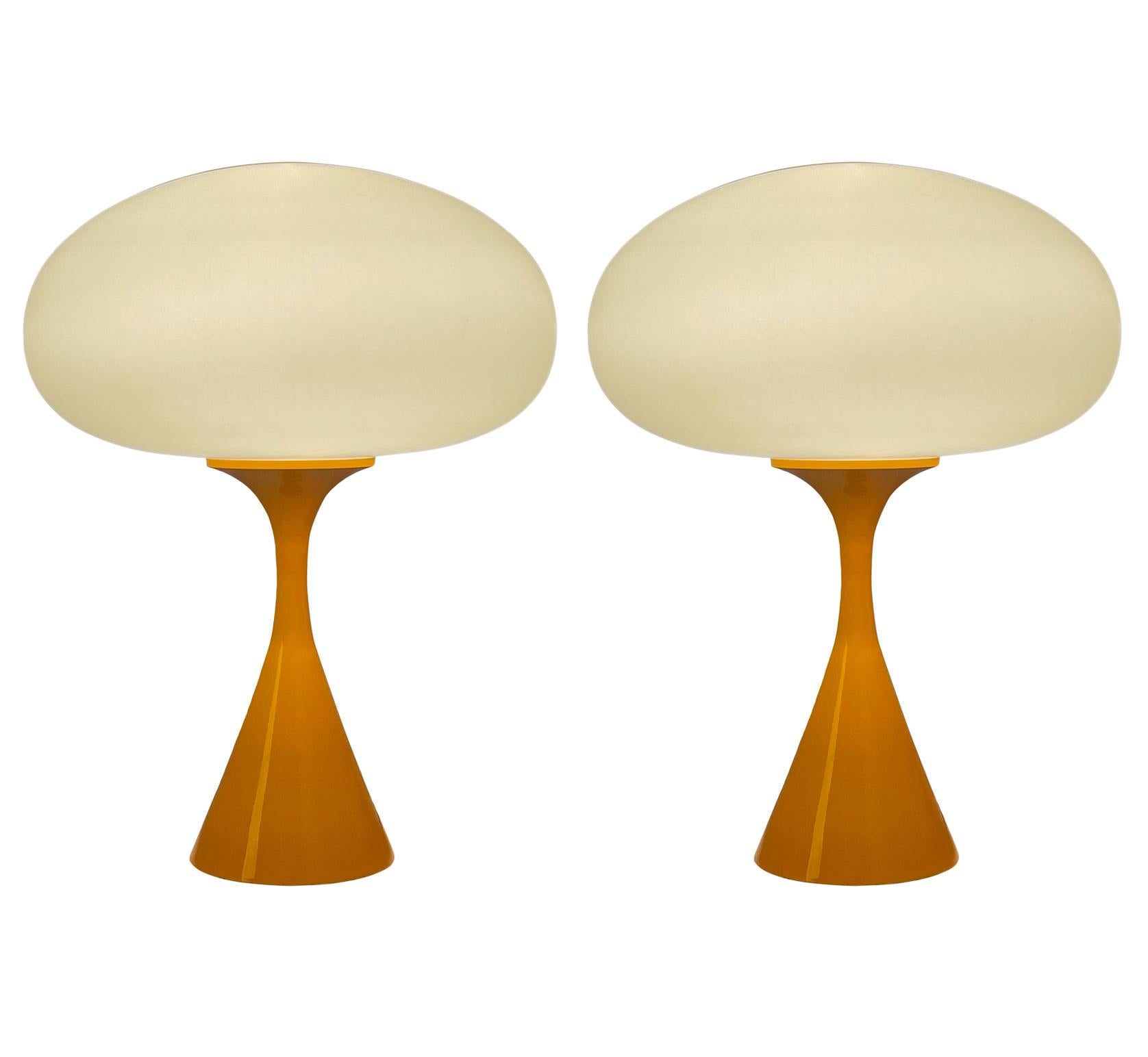 A handsome matching pair of table lamps in a conical mushroom form after Laurel Lamp Company. The lamp features a cast aluminum base with an orange powder coat and a mouth blown frosted glass lamp shade. Price includes the pair as shown.