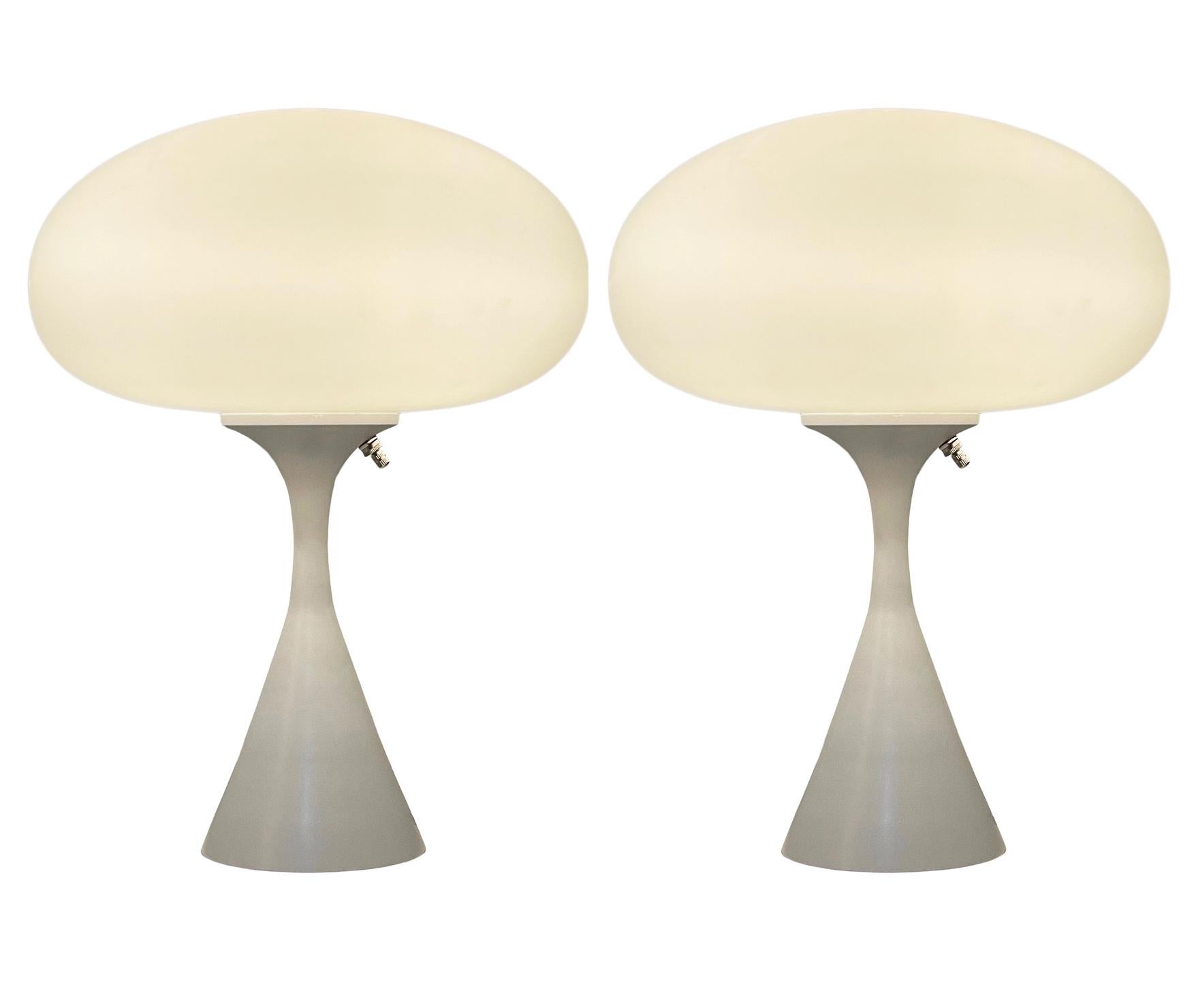 A handsome matching pair of table lamps in a conical mushroom form after Laurel Lamp Company. The lamp features a cast aluminum base with a white powder coat and a mouth blown frosted glass lamp shade. Price includes the pair as shown.
