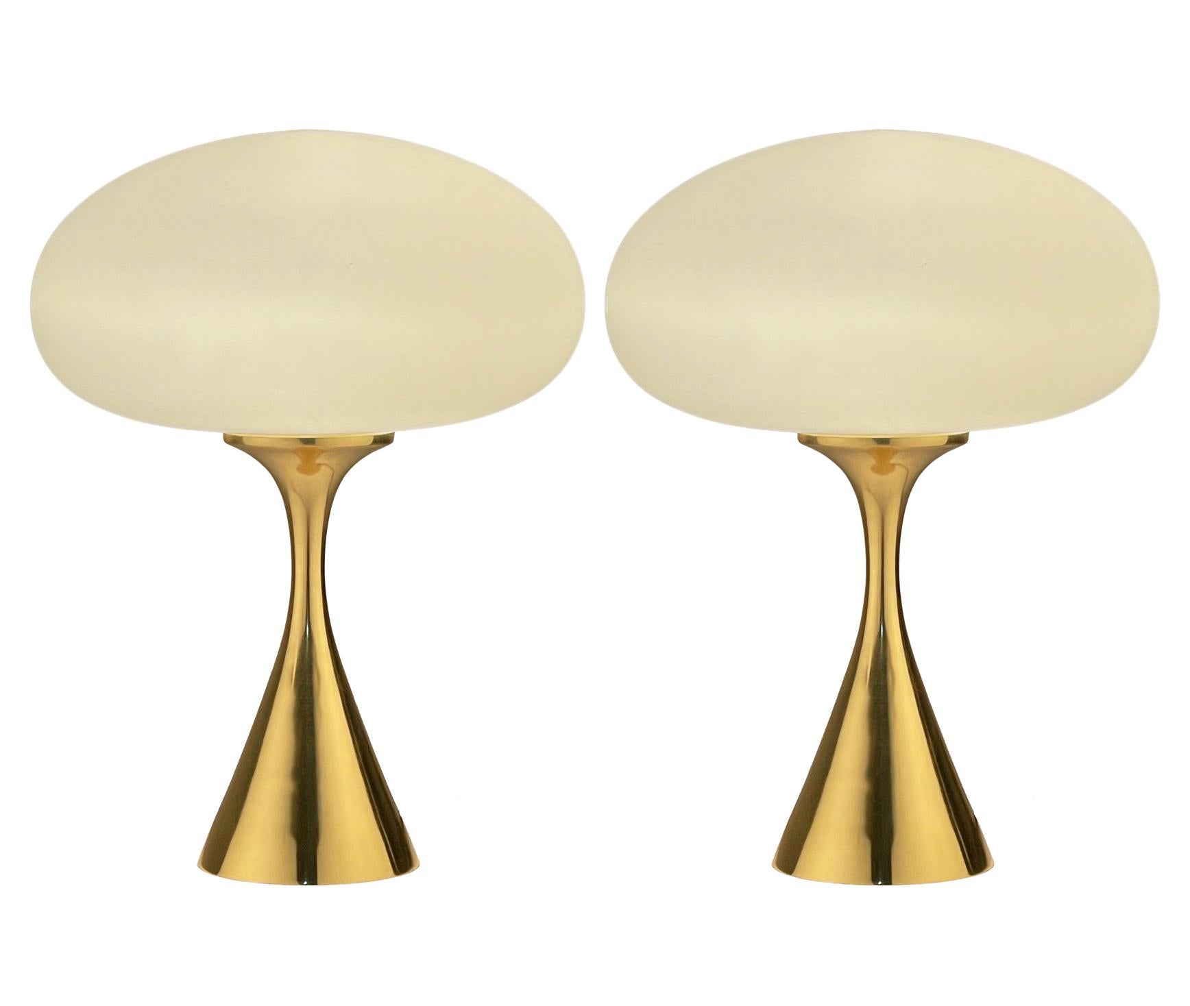 A handsome matching pair of table lamps in a conical mushroom form after Laurel Lamp Company. The lamps feature brass plated cast aluminum base with a mouth blown frosted glass lamp shade. Price includes the pair as shown.