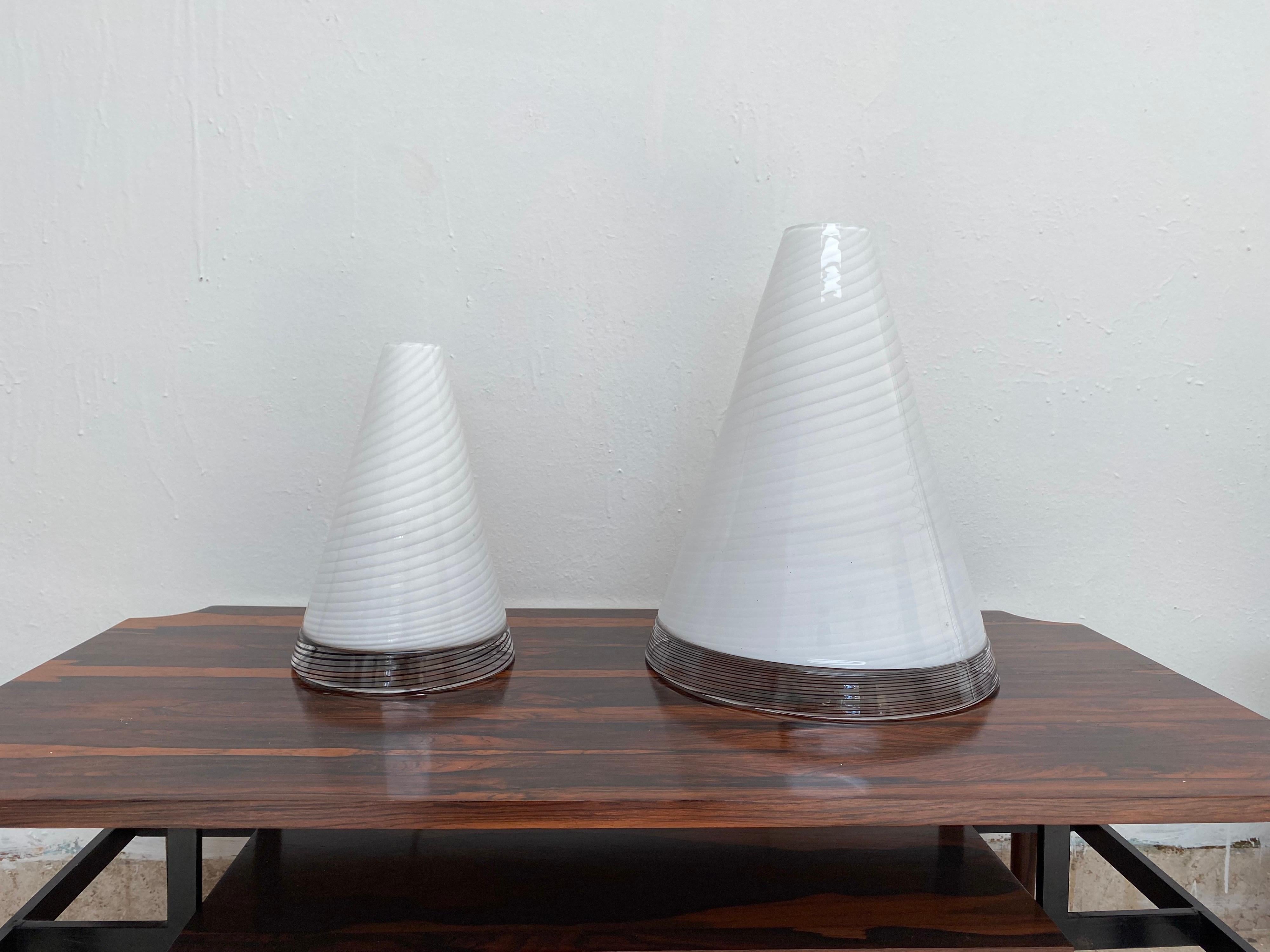 Mid-Century Modern set of table lamps executed in Hand-blown Murano Glass in the shape of Cones. 
The top is in a white swirl pattern and the base in black “tessuto”. 
Both have the original labels that read “GT, Toso Selezione, Murano” (faintly