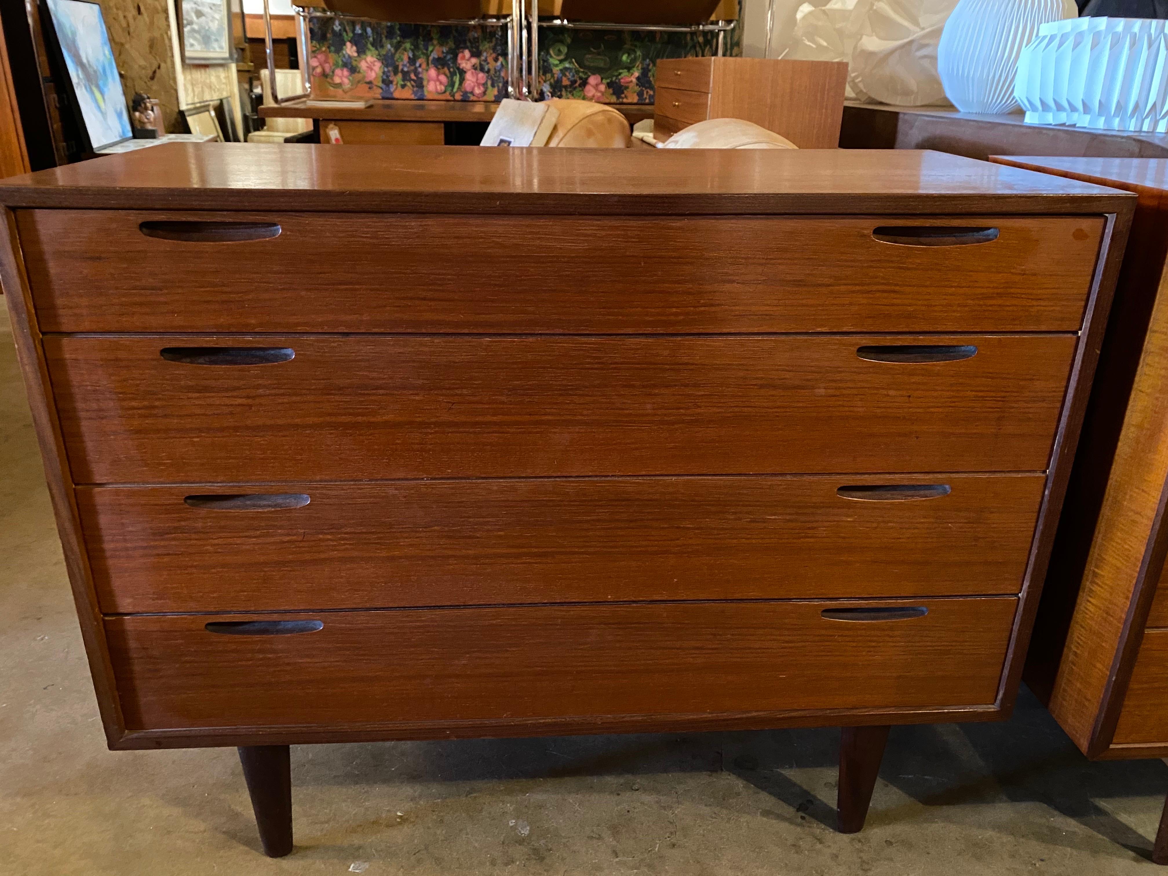 Pair of mid-century modern dressers with a finished back, sculpted pull handles, and four drawers made of teak designed by Kofod-Larsen for J Clausen. Circa 1950s, Denmark. This pair of mid-century modern dressers are in good overall condition and
