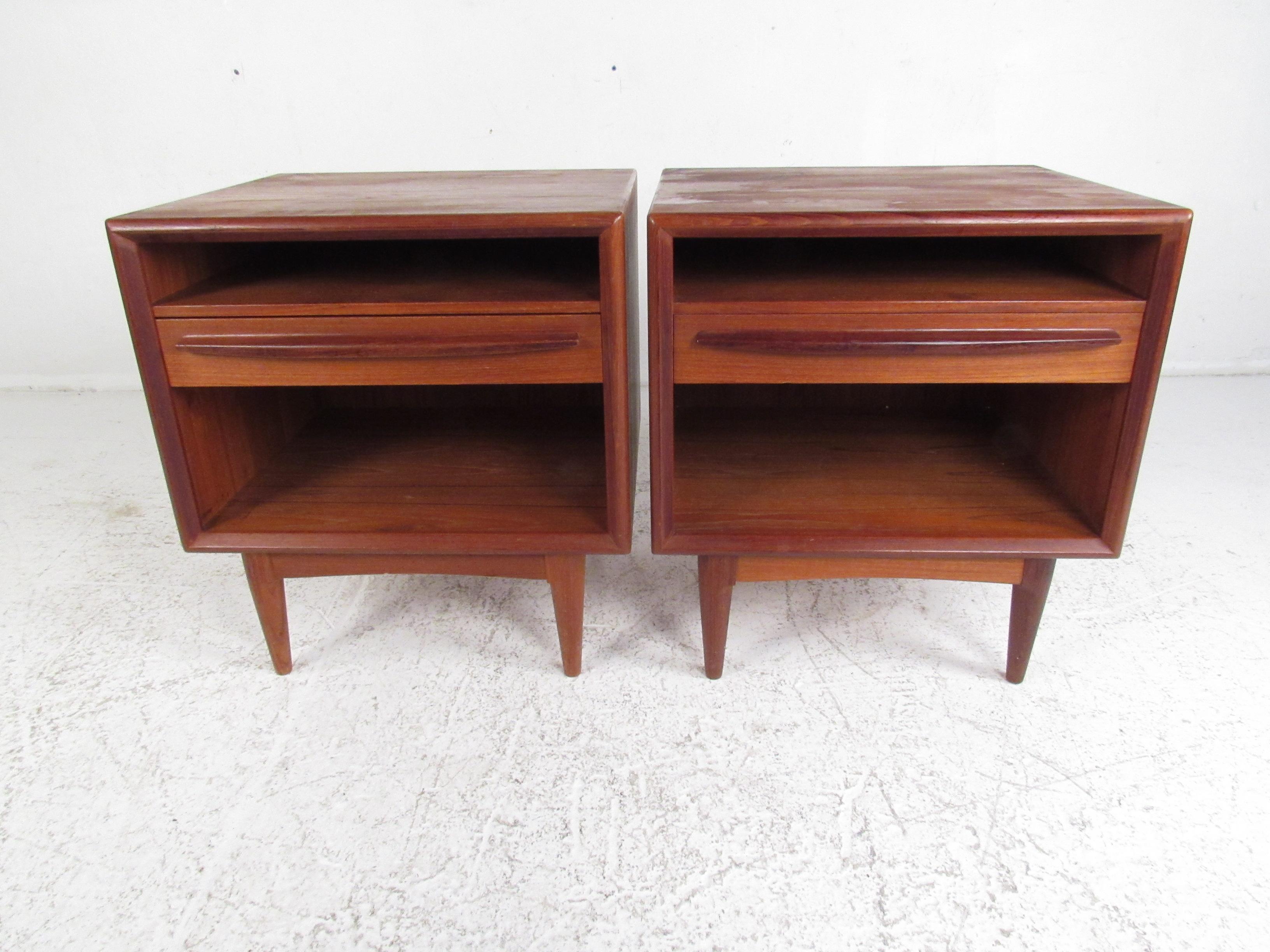 This beautiful pair of vintage modern nightstands feature one drawer and two open compartments for storage. A unique design with a sculpted horizontal drawer pull, a finished back, and tapered legs. This Danish teak pair of end tables make the