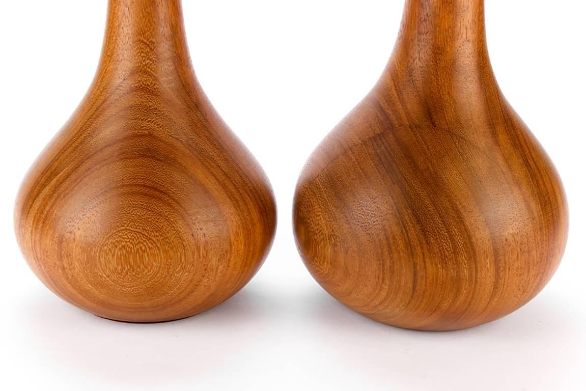 Pair of midcentury teak wood table lamps, narrow necks leading down to a bulbous form base with felted bottom.

Condition: Expected wear and signs of use including some minor surface scratching.