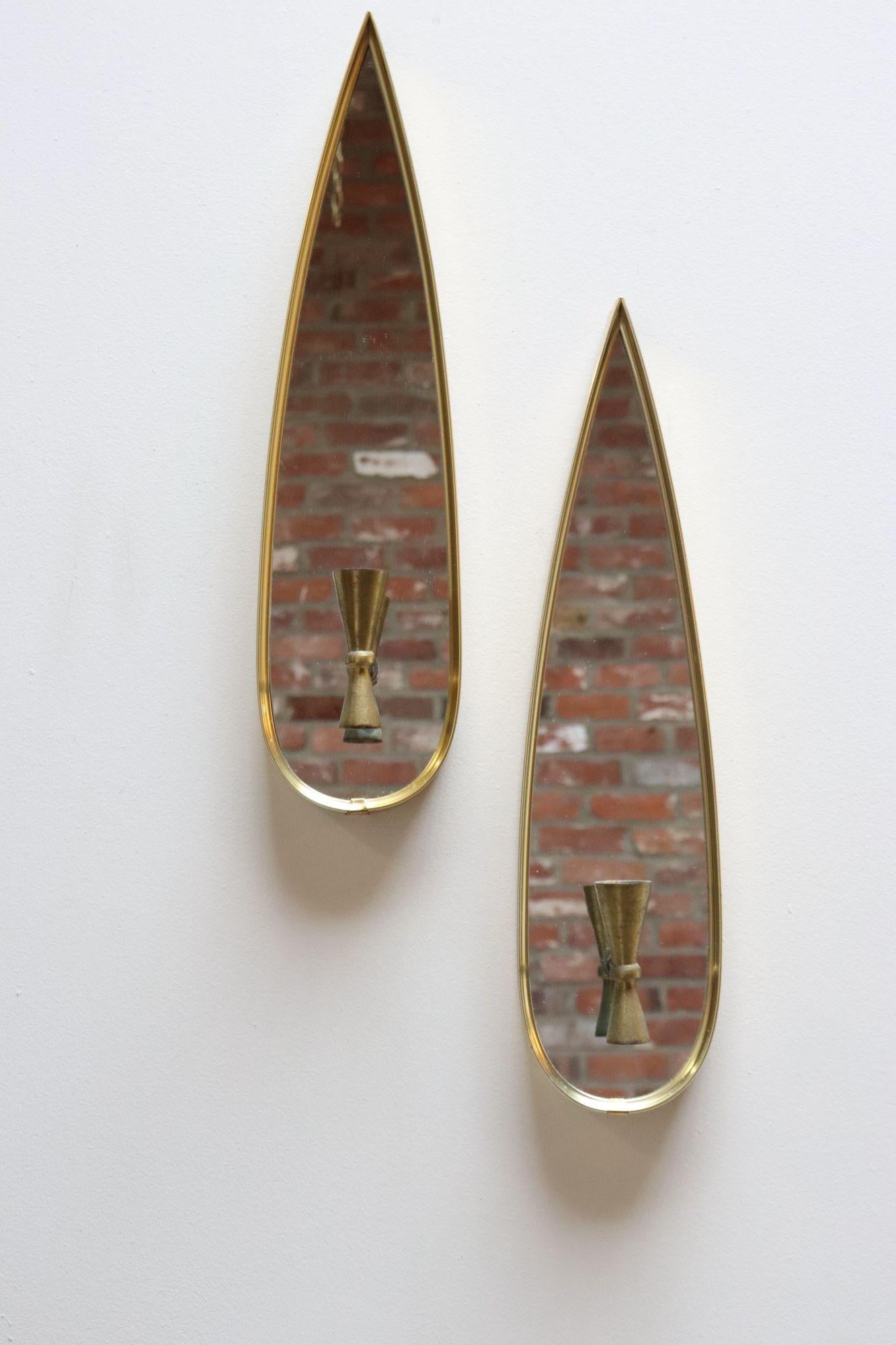Paire d'appliques murales en forme de flamme ou de goutte d'eau composées de cadres en aluminium anodisé doré et de porte-bougies en laiton à double cône/diabolo (vers les années 1950, États-Unis).
L'orientation du porte-bougie peut être modifiée
