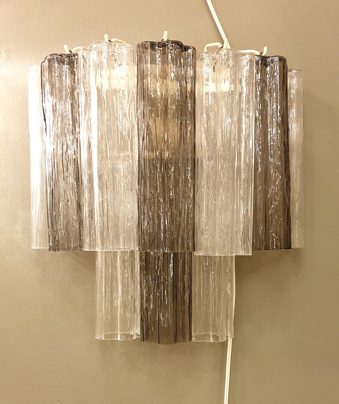 Pair of Mid-Century Modern two colors Venini Tronchi Murano glass sconces, Italy, 1970s.
The pairs of sconces alternates transparent and beige colors of glass.
The frame is painted in ivory
The sconces have 2 lights each: rewired with candelabra