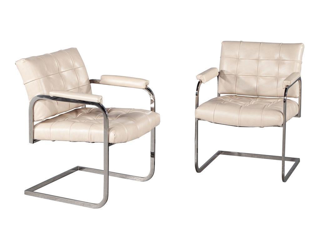 Pair of Mid-Century Modern tufted cream leather Accent chairs. American, circa 1970’s, fully restored in beautiful Italian cream leather. Tufted detailing with accent nail heads. Completed with iconic Milo Baughman Inspired curved stainless steel