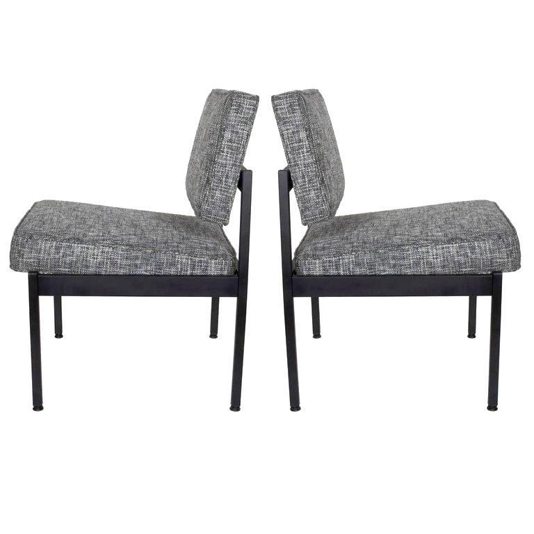 Pair of upholstered Mid-Century Modern industrial style chairs with floating seat and back cushions. Fine example of utilitarian furniture, great as office chairs or easy chairs. Satin black enameled metal frame is complimented by newly upholstered