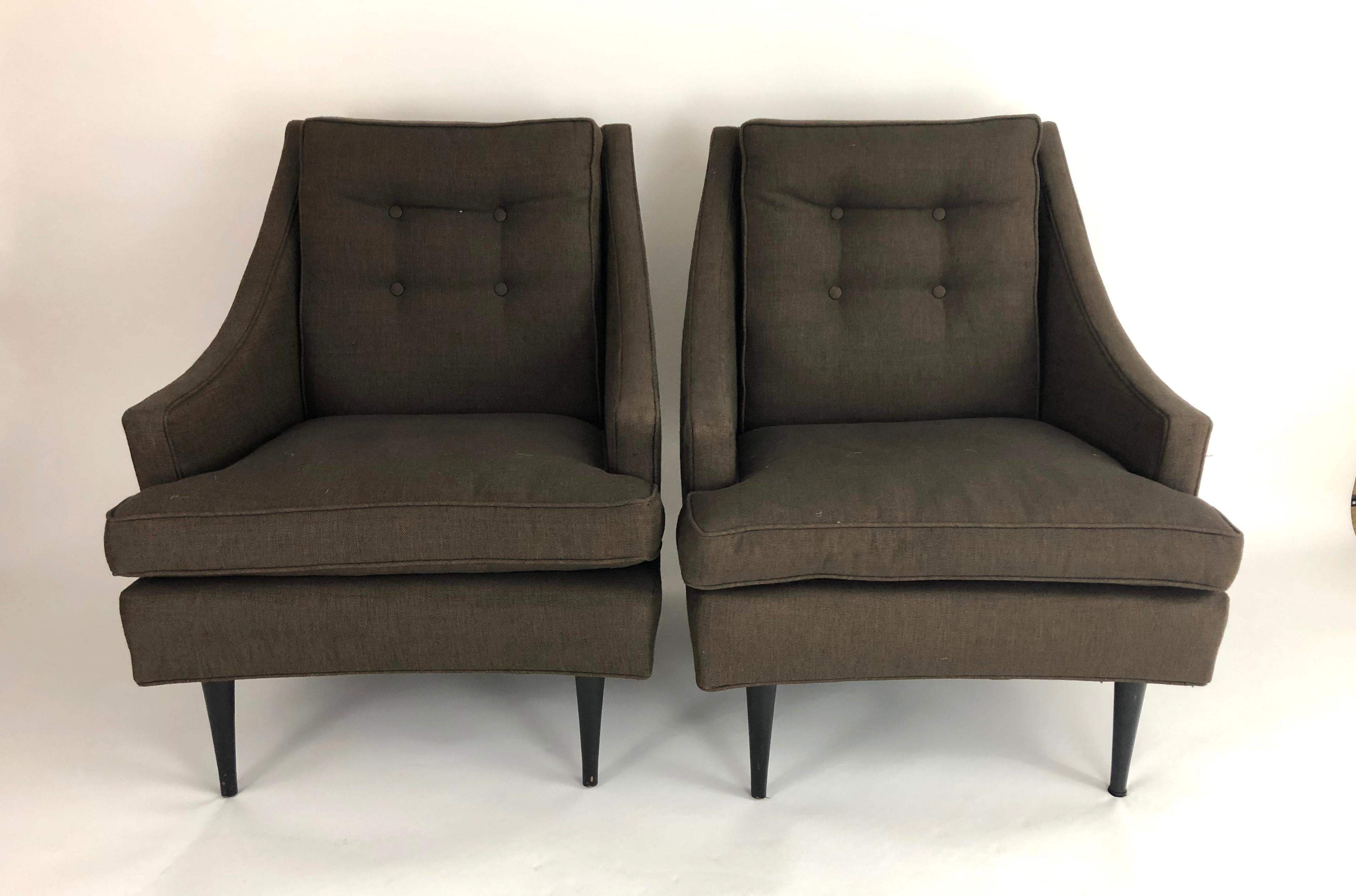 A pair of comfortable and well made Mid-Century Modern period lounge chairs, upholstered in brown linen with button tufted back cushions and spring down seat cushions, with four black painted tapering cylindrical hardwood legs. Great form, with down