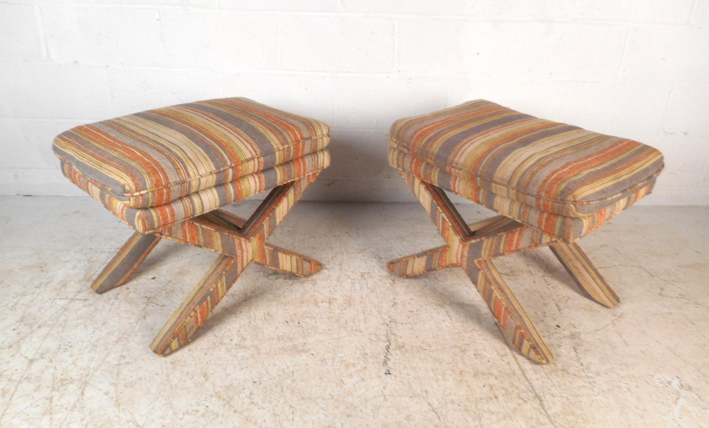 These unique midcentury ottomans feature plush padded rests atop an eye-catching cross-base frame. A striped vintage upholstery covers both the base and seat, providing a stylish continuity throughout the design. Please confirm item location (NY or