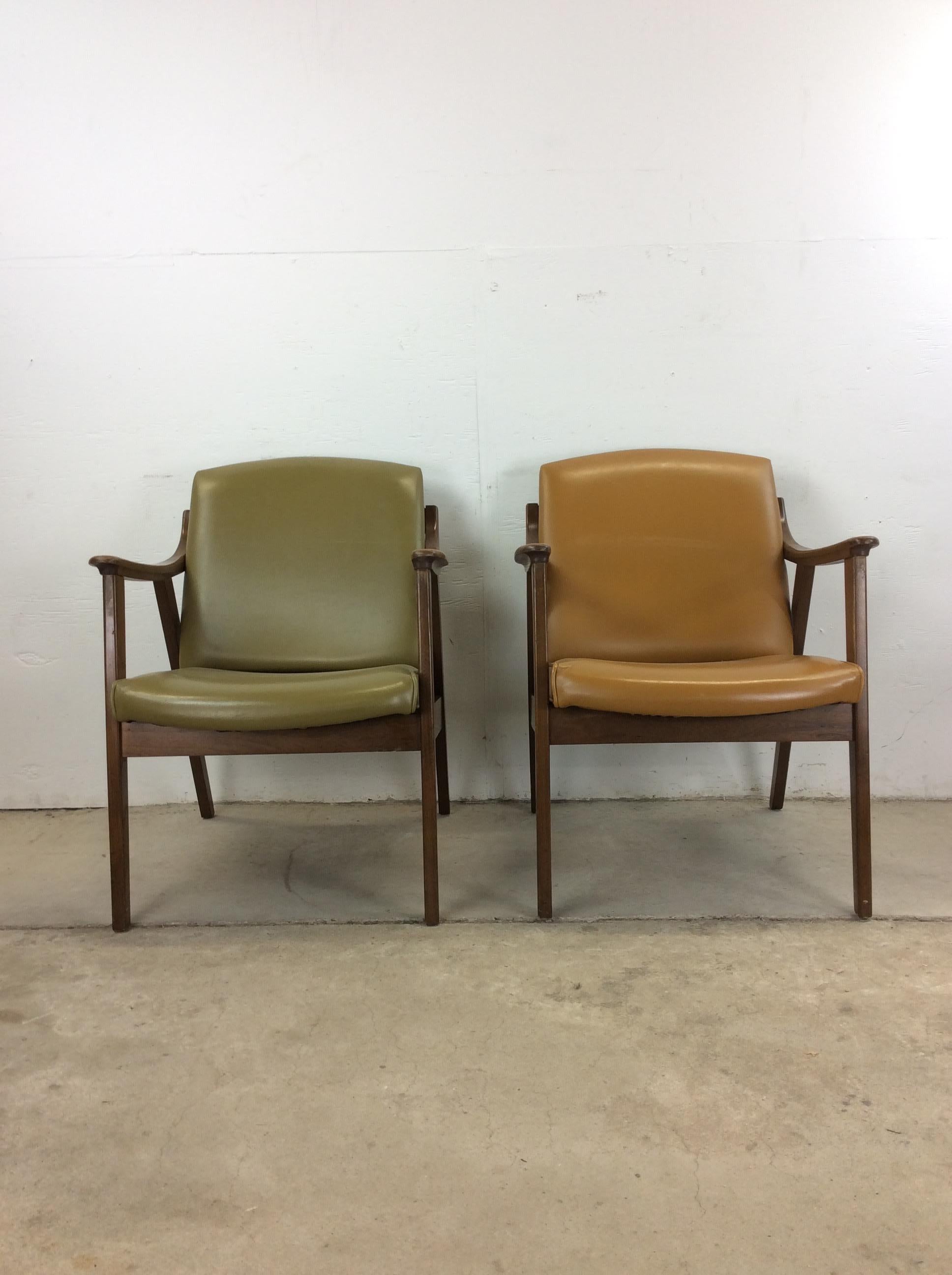 Cette paire de chaises de salon modernes du milieu du siècle présente des cadres en bois dur, une finition originale en noyer, des accoudoirs sculptés, de hauts pieds fuselés et un revêtement en vinyle vintage or et vert. 

Dimensions : 24.25w 28d