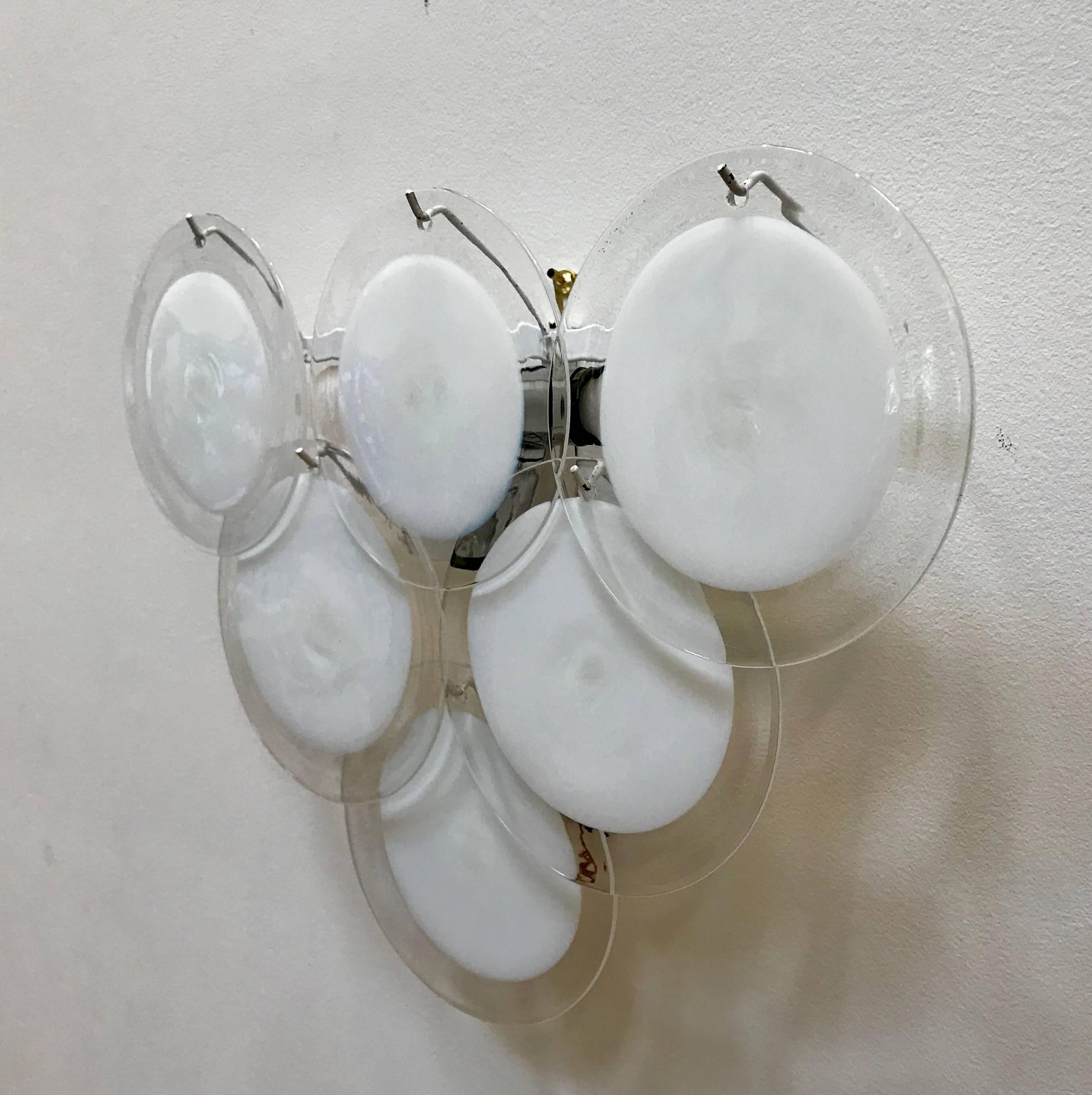 Very nice pair of Vistosi wall sconces, Murano, Italy, 1970s. Each handblown clear and milk white glass disc hangs from the metal wall-mounted fixture. One chrome socket cover is missing, please see photo.