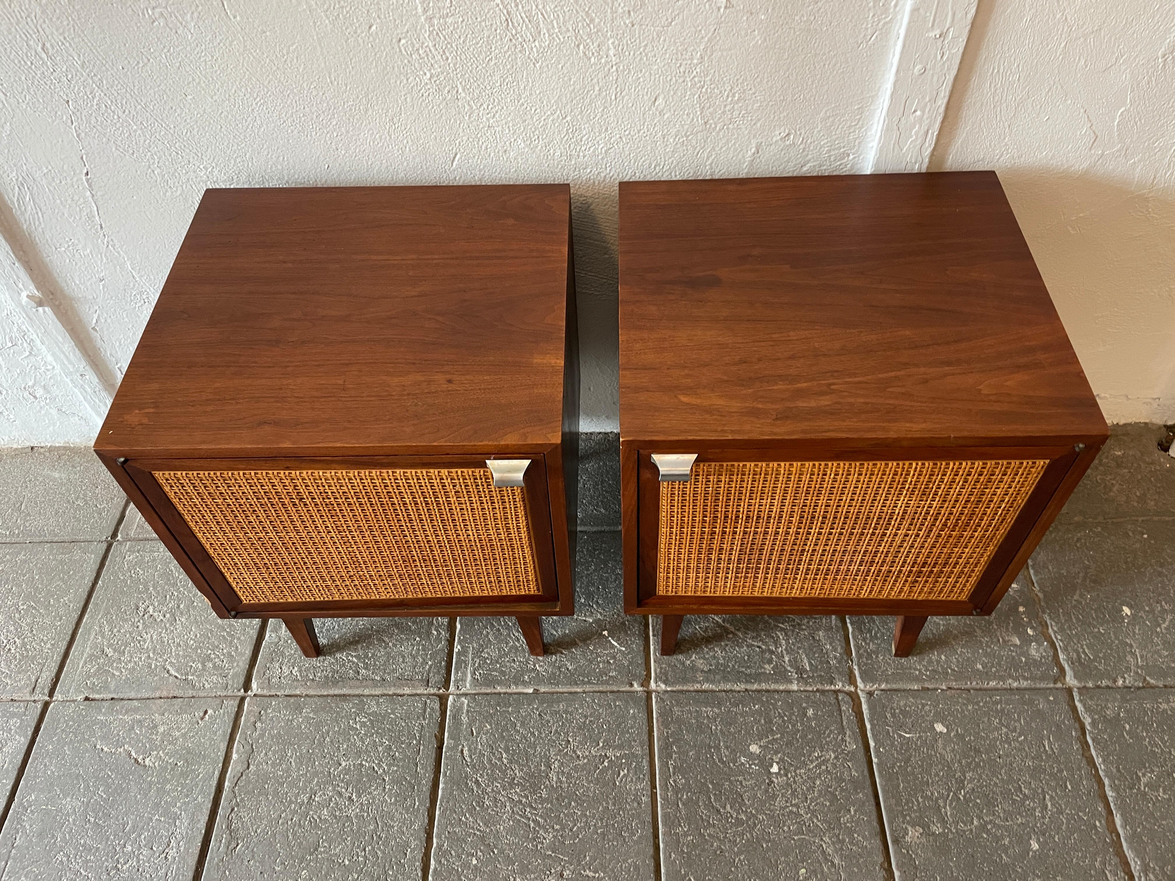 Pair of Mid-Century Modern walnut with cane door nightstands. Beautiful design and perfect size. Nice walnut grain with aluminum handle. Cane door fronts are perfect. Each nightstand has 1 adjustable shelf inside. Sits on solid walnut base with