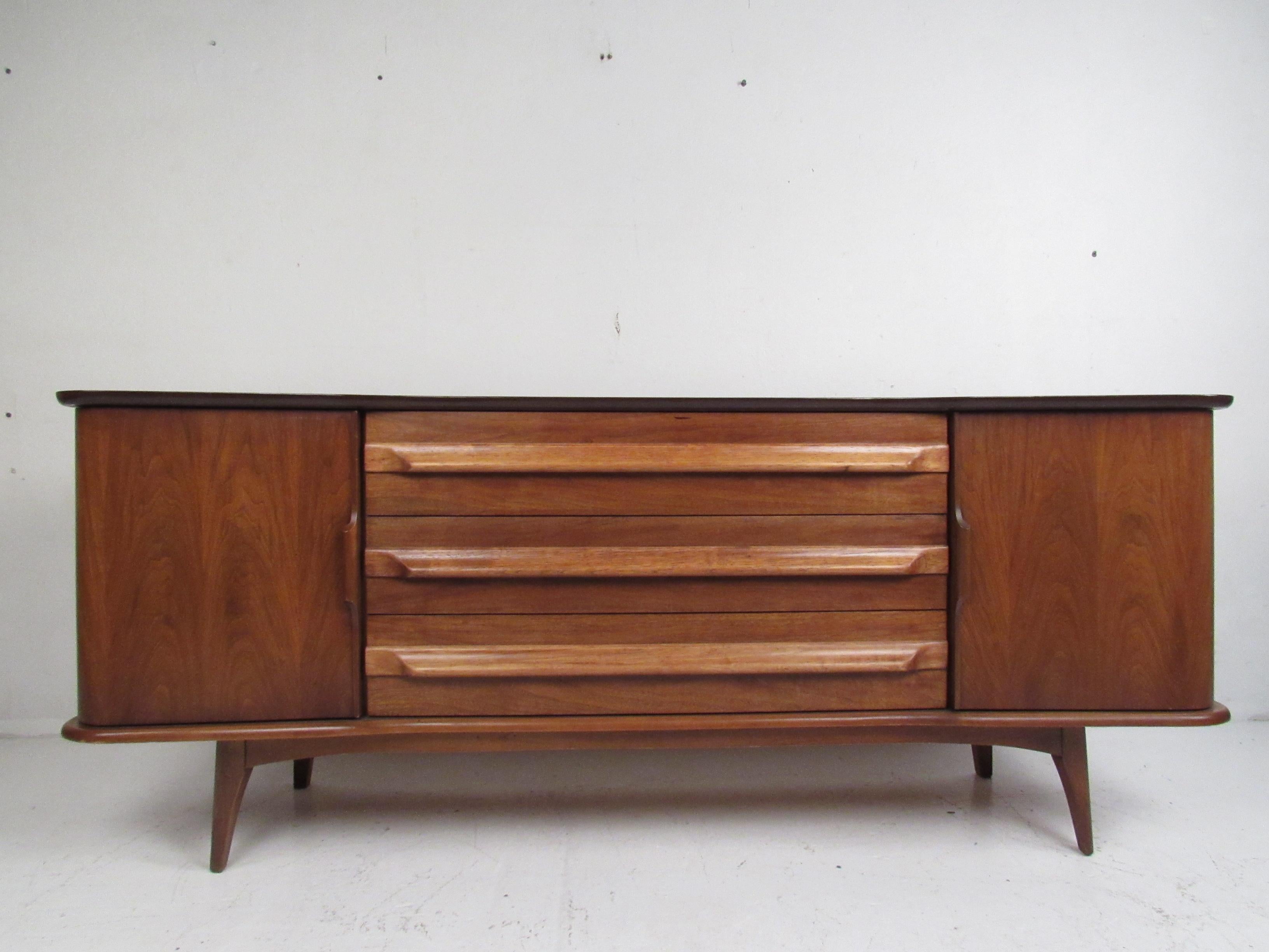A vintage modern bedroom set that boasts a two-tone design with oak and walnut wood. This stunning pair offers plenty of room for storage within their many dovetailed drawers. A unique curved top, sculpted cabinet pulls, and splayed legs add to the