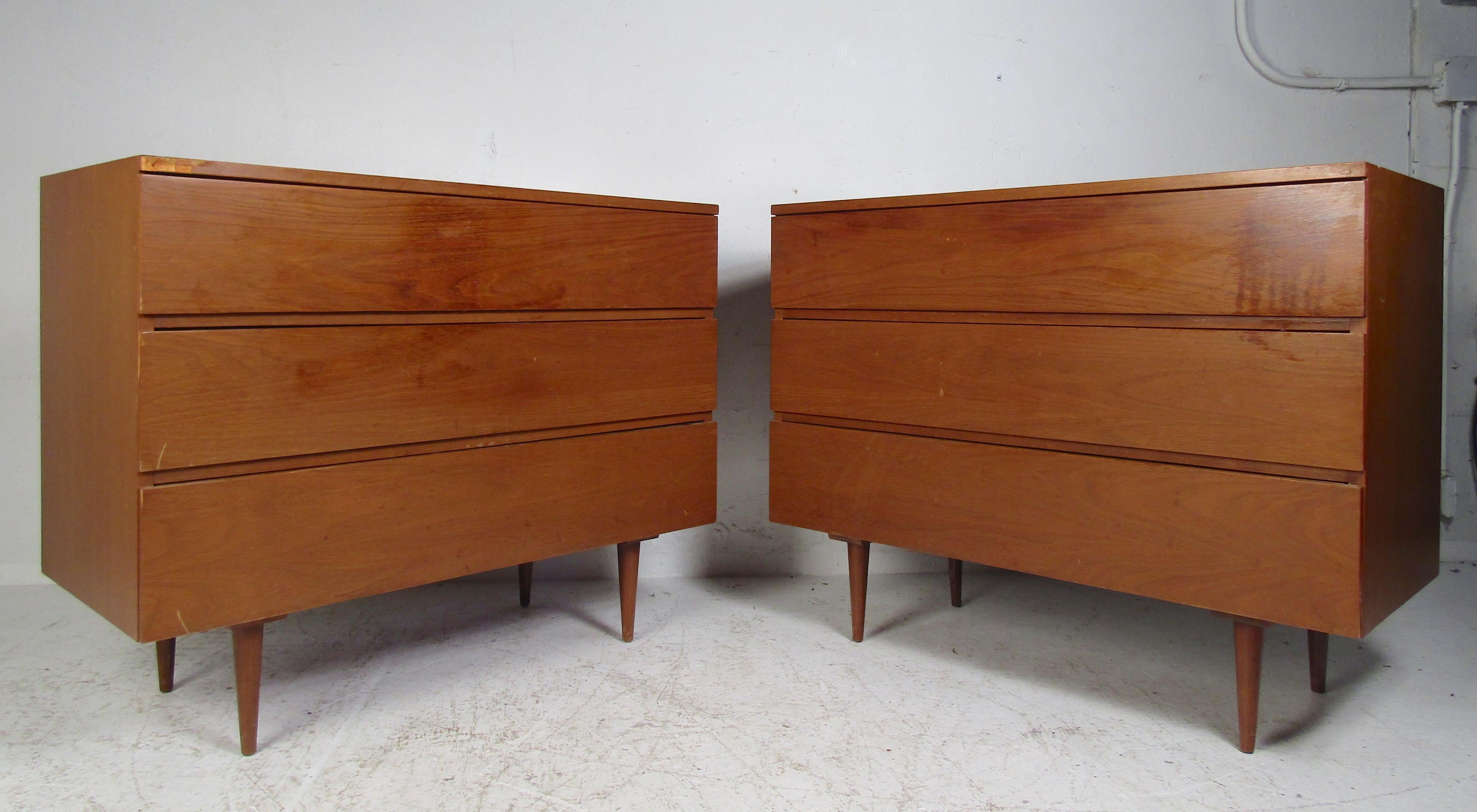 This beautiful pair of vintage modern chests have three drawers ensuring plenty of space of storage. Straight line design with hidden drawer pulls, a vintage walnut finish, and tapered legs. This lovely pair makes the perfect addition to any modern