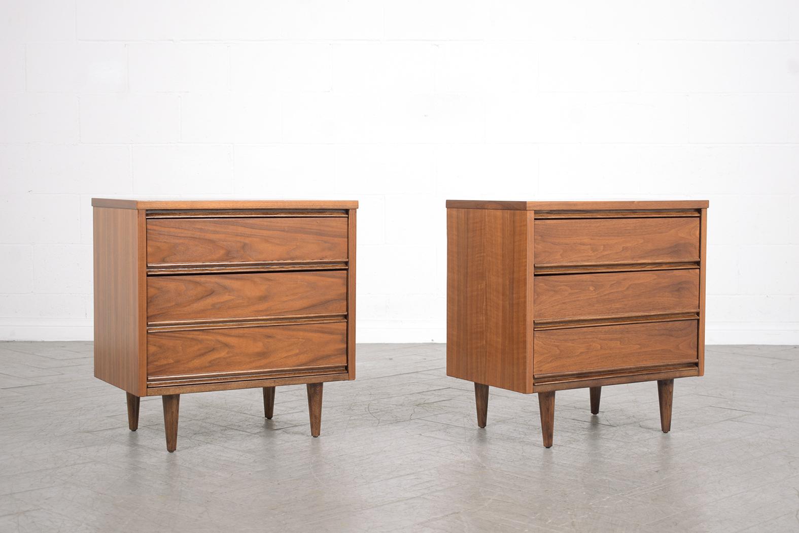 This Pair of 1960s vintage mid-century modern nightstands are crafted out of walnut wood that has been stained in a rich mahogany color with a polished finish and has been fully restored by our team of in-house craftsmen. This set of end tables