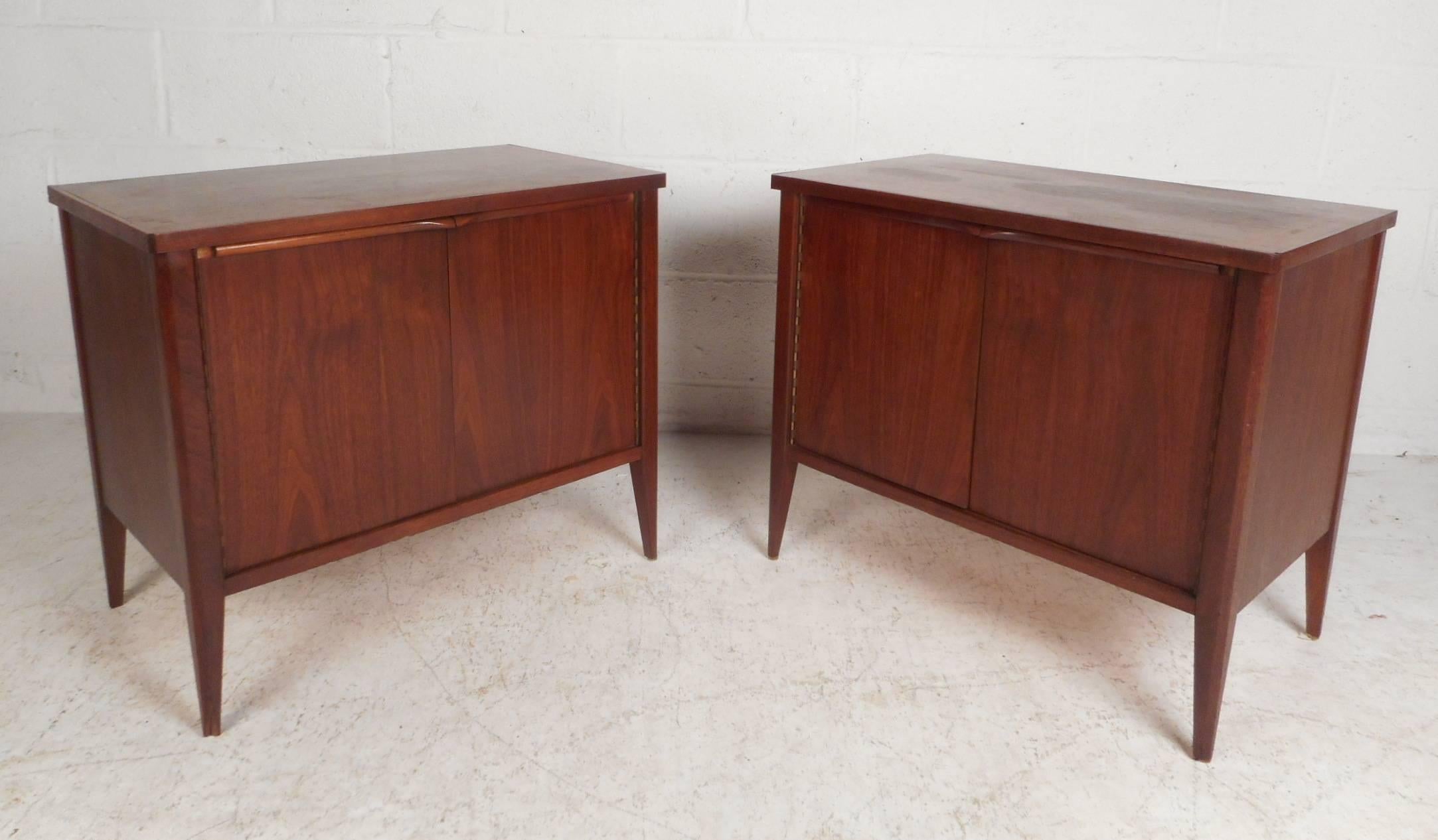 Stunning pair of midcentury end tables with unusual sculpted pulls on the top of each cabinet door. Sleek and functional design with an abundance of room for storage on the interior along with a removable shelf for convenience. Quality craftsmanship