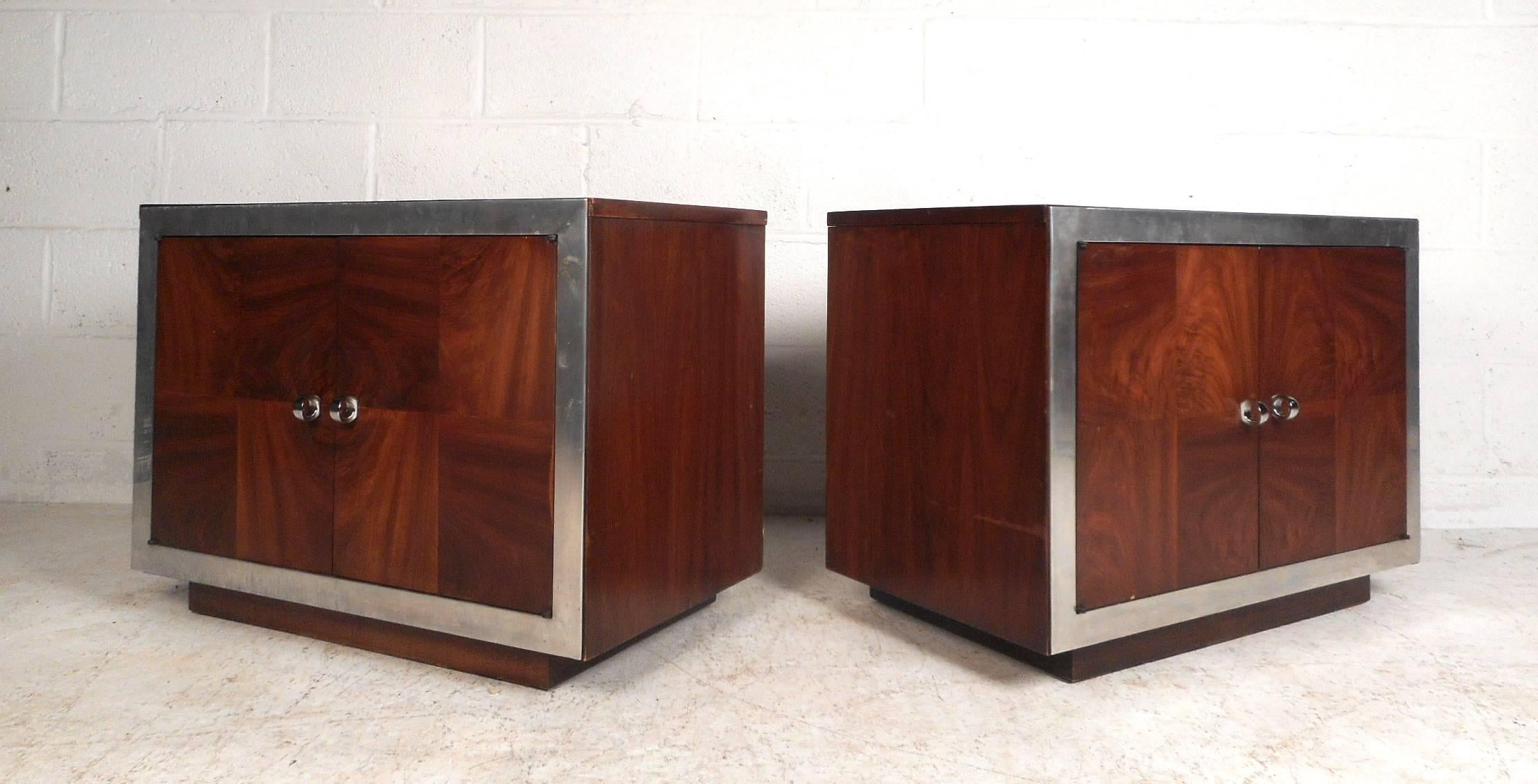 This amazing pair of vintage modern end tables feature unique circular chrome pulls on each cabinet door front. Unusual case pieces with chrome trim wrapped around the front and elegant dark walnut wood grain running in different directions