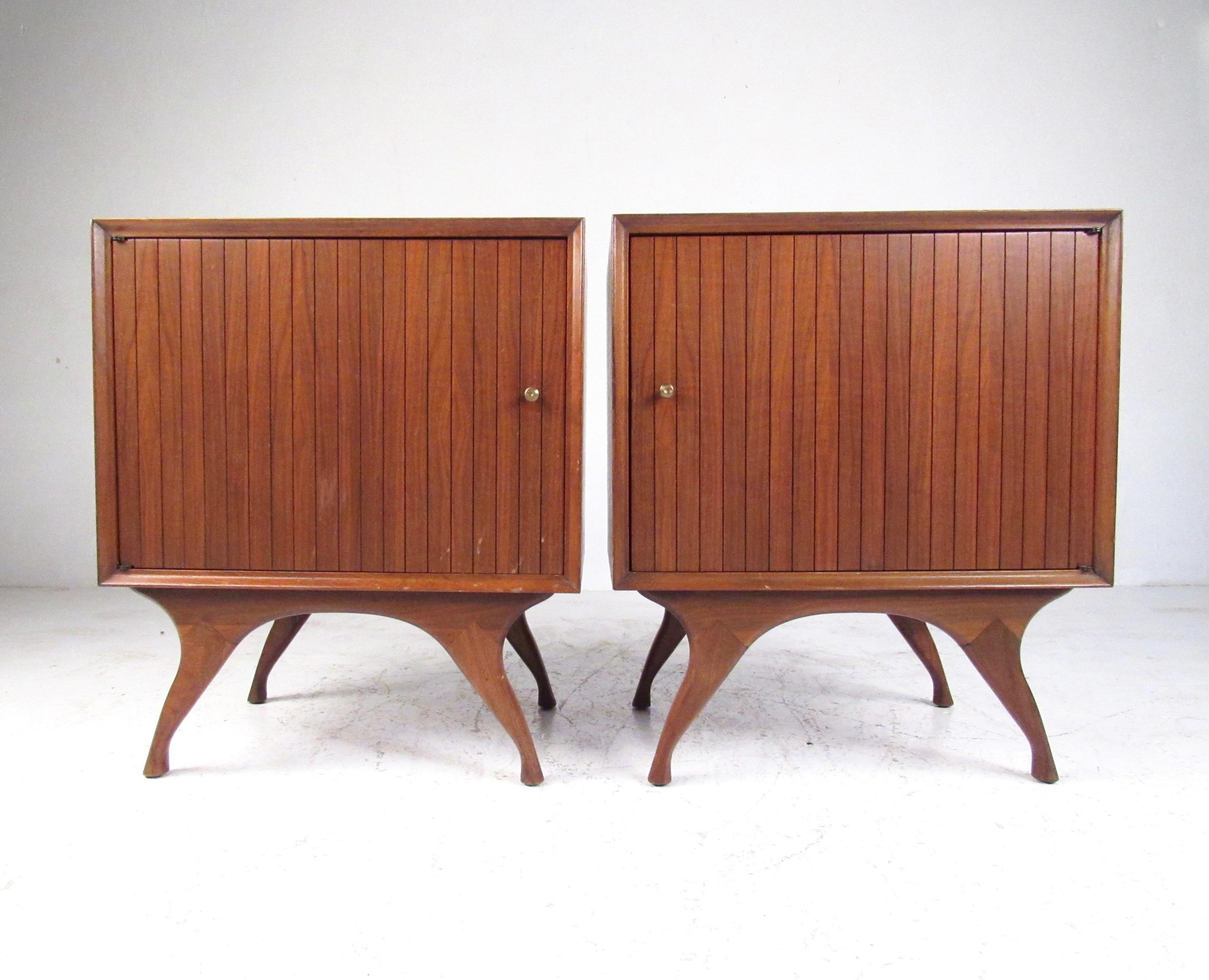The shapely design of this matched pair of vintage walnut nightstands features sculpted legs, slatted cabinet doors, and adjustable shelf storage. Perfect set of Mid-Century Modern bedside tables offer storage and style, please confirm item location