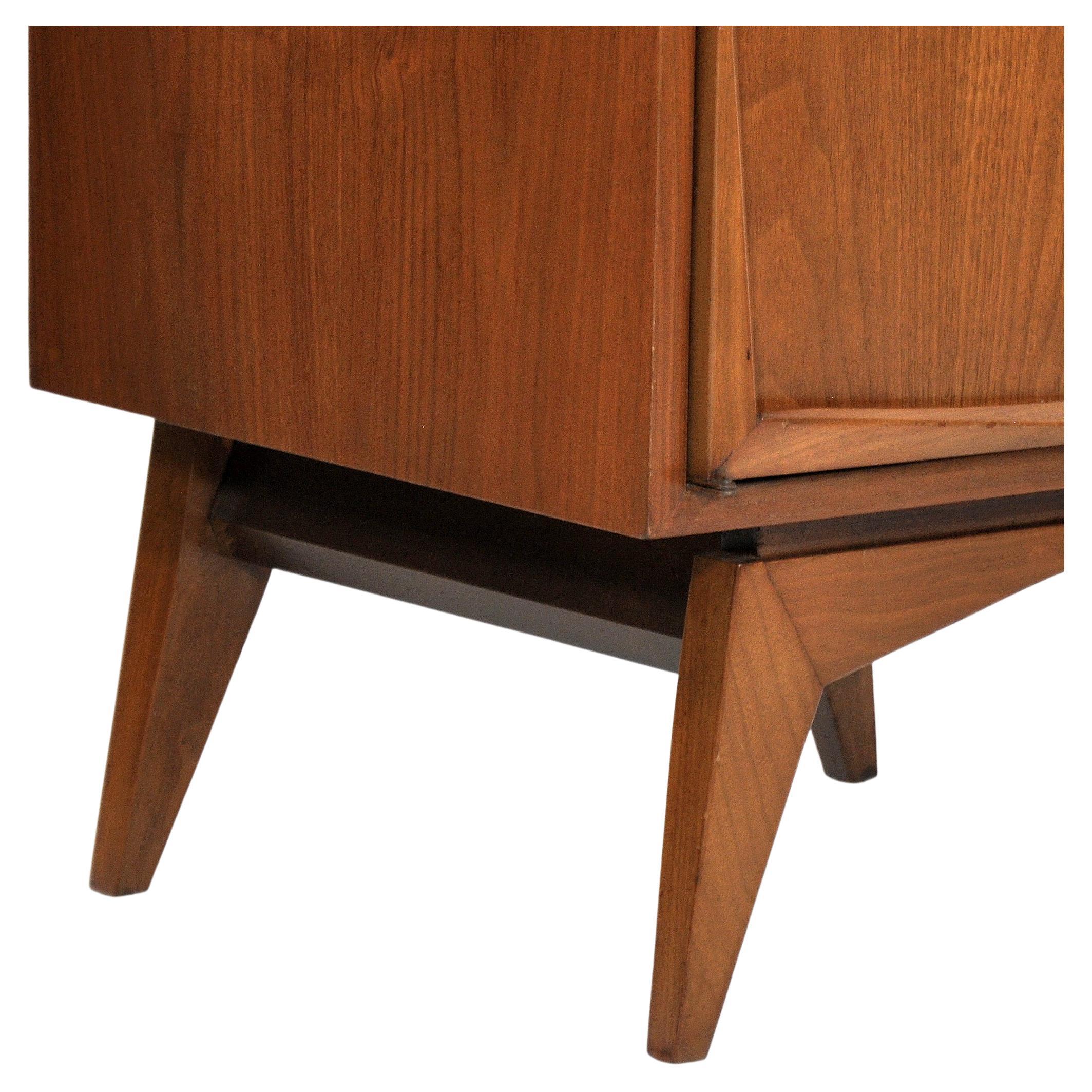 A striking pair of vintage walnut end or bedside tables dating from the late 1950s to early 1960s. The sculptural occasional tables features a cabinet door with sculpted fronts opening to an interior fitted with a glass shelf, resting on a base with