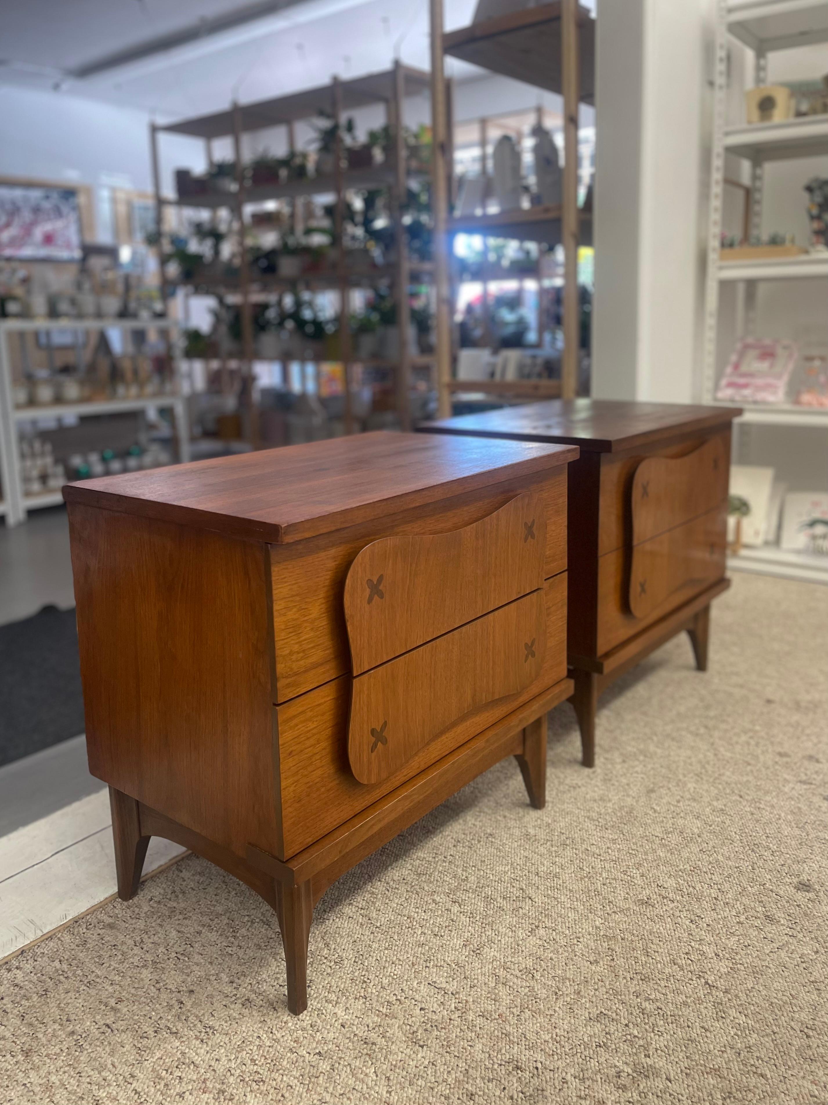  This matching pair of mid century modern nightstands was manufactured likely in the 1960s and marked with model number B5180-67-270 and the designation N-Table on the back panel.
Constructed from walnut with richly grained veneer, these nightstands