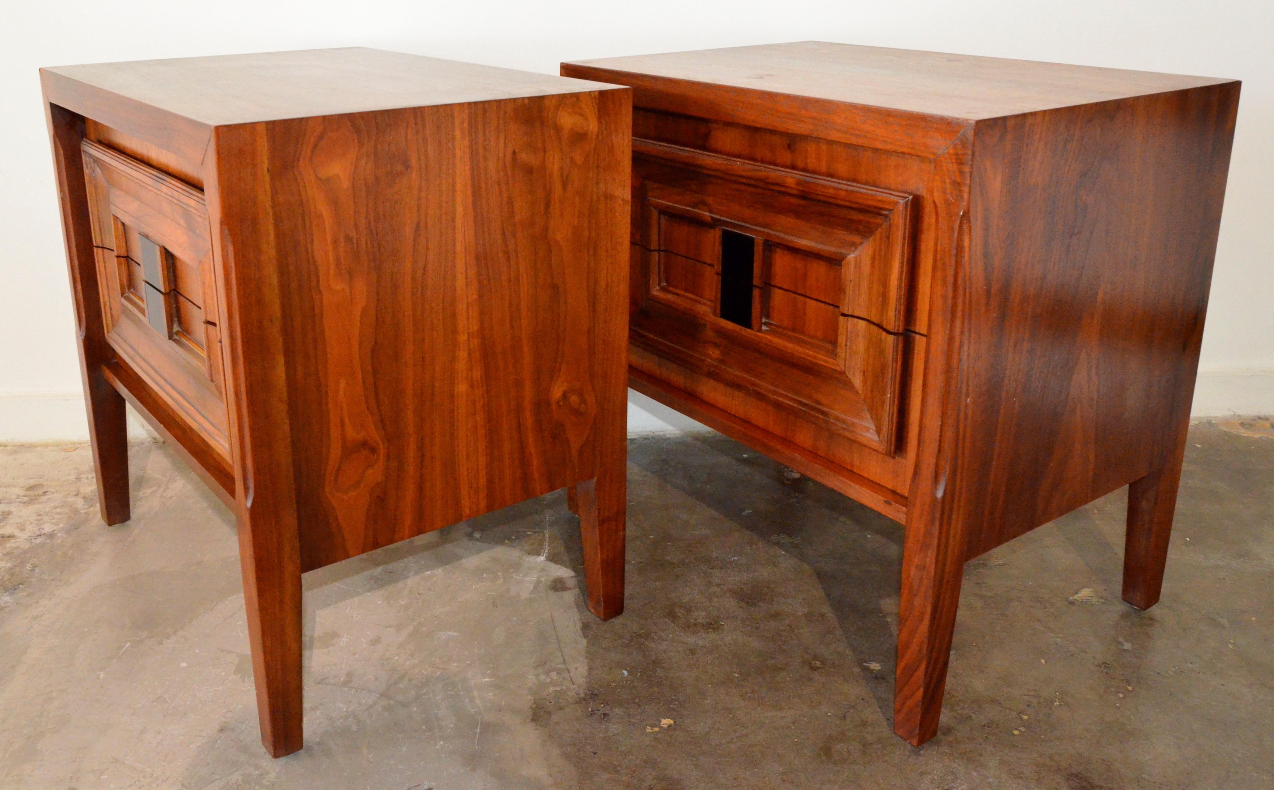 Offered are a pair of Mid-Century Modern Brutalist walnut veneer and burl wood bedside night stands / side or end tables. The bedside tables are box two-drawer cabinets on raised legs. The burl wood on these bedside stands / tables make for a
