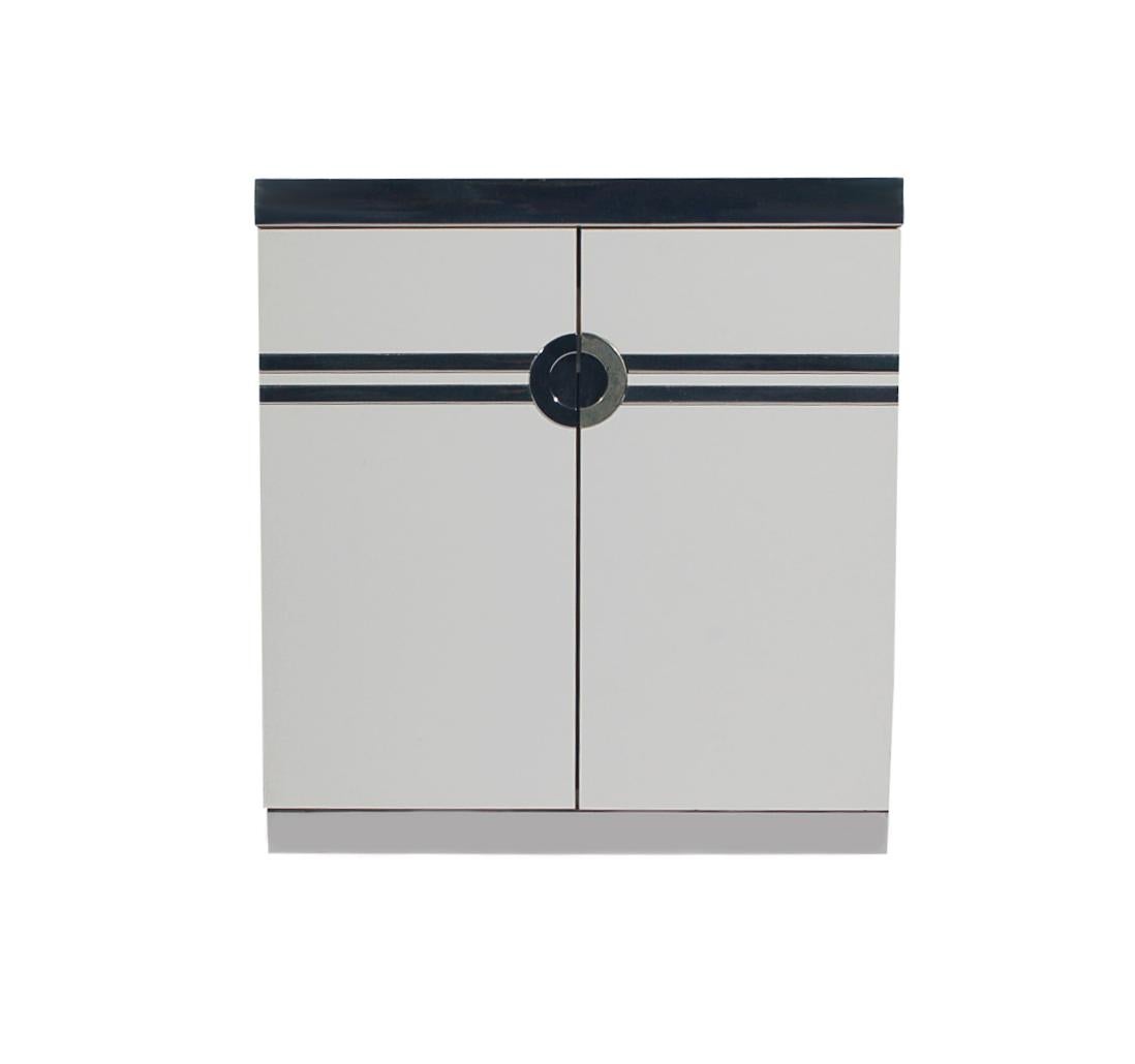 A lovely pair of nightstands designed by Pierre Cardin in the 1970s and produced in France. These feature white lacquer with polished steel trim in a Classic Art Deco design. Each has an interior pullout / pull-out drawer and shelf. Manufactures
