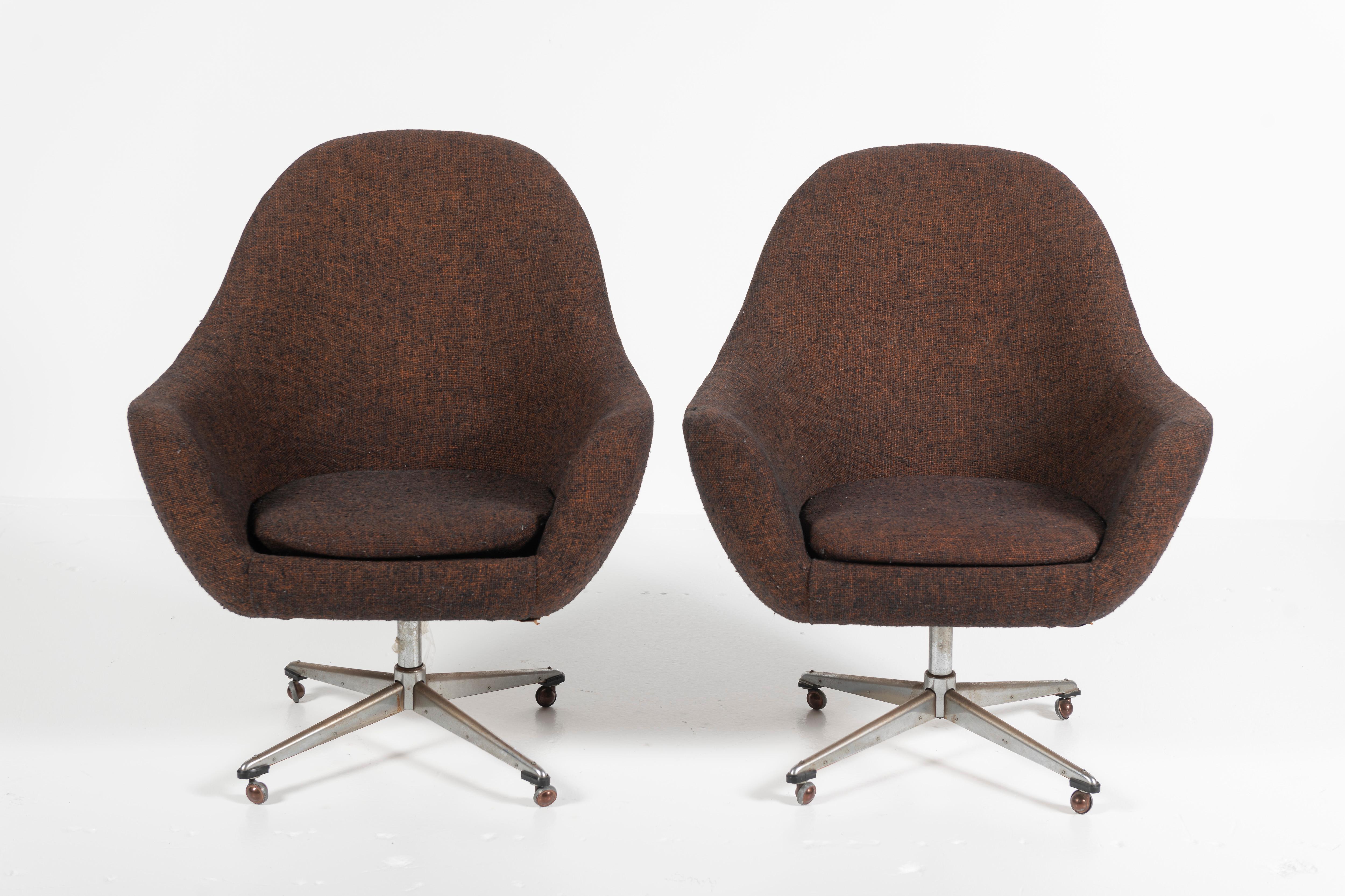 This modern pair of brown wool tweed Pod Swivel Armchairs by Overman, Sweden, have chrome legs and casters. The classic design utilizes high quality foam to create a comfortable seat, also enhanced by the curved egg shape. This edition has a