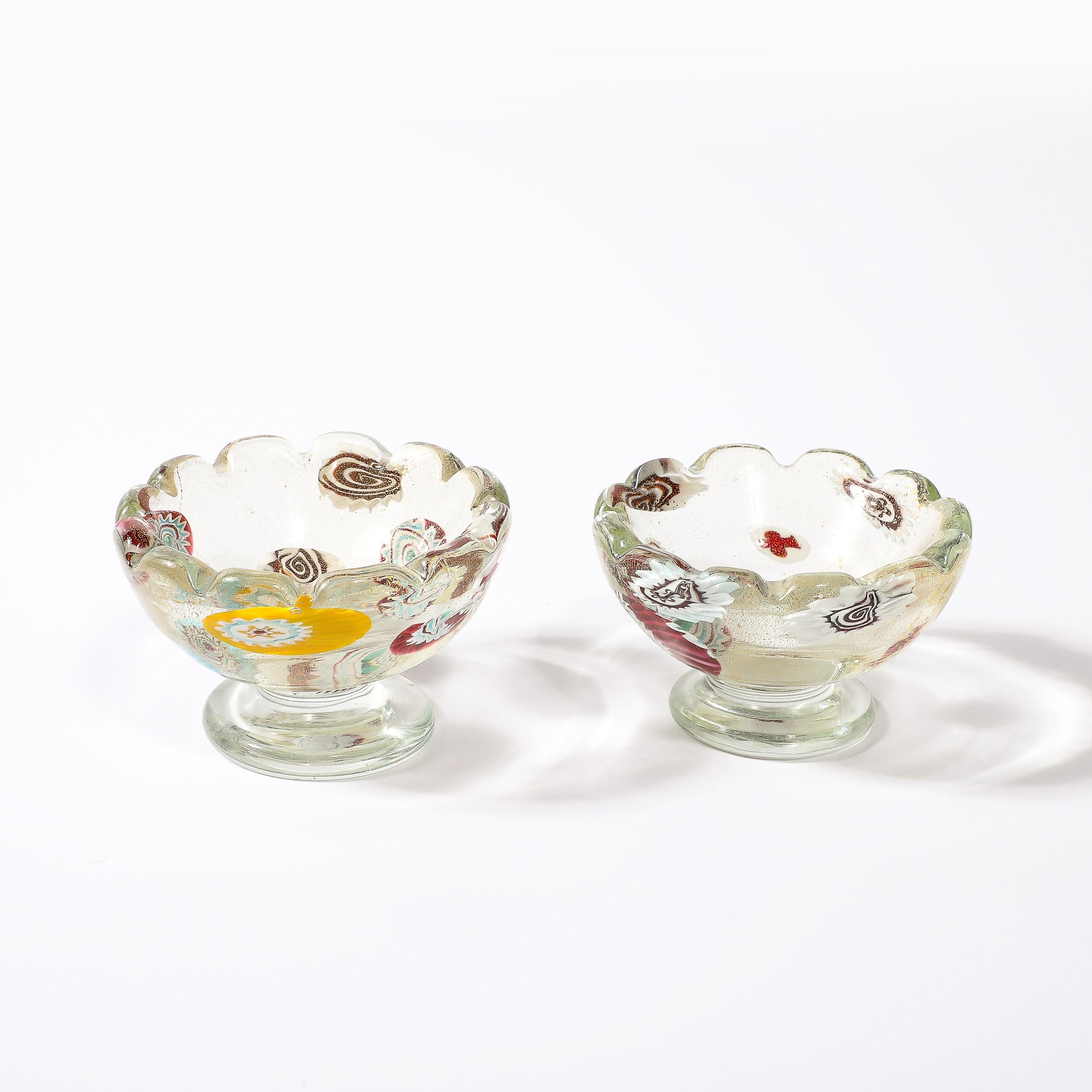 Cette charmante paire de bols en verre de Murano soufflé à la main, de style moderniste du milieu du siècle, avec bords festonnés et décorations Millefiori avec mouchetures d'or 24 carats, est originaire d'Italie, vers 1950. Ces bols sont posés sur