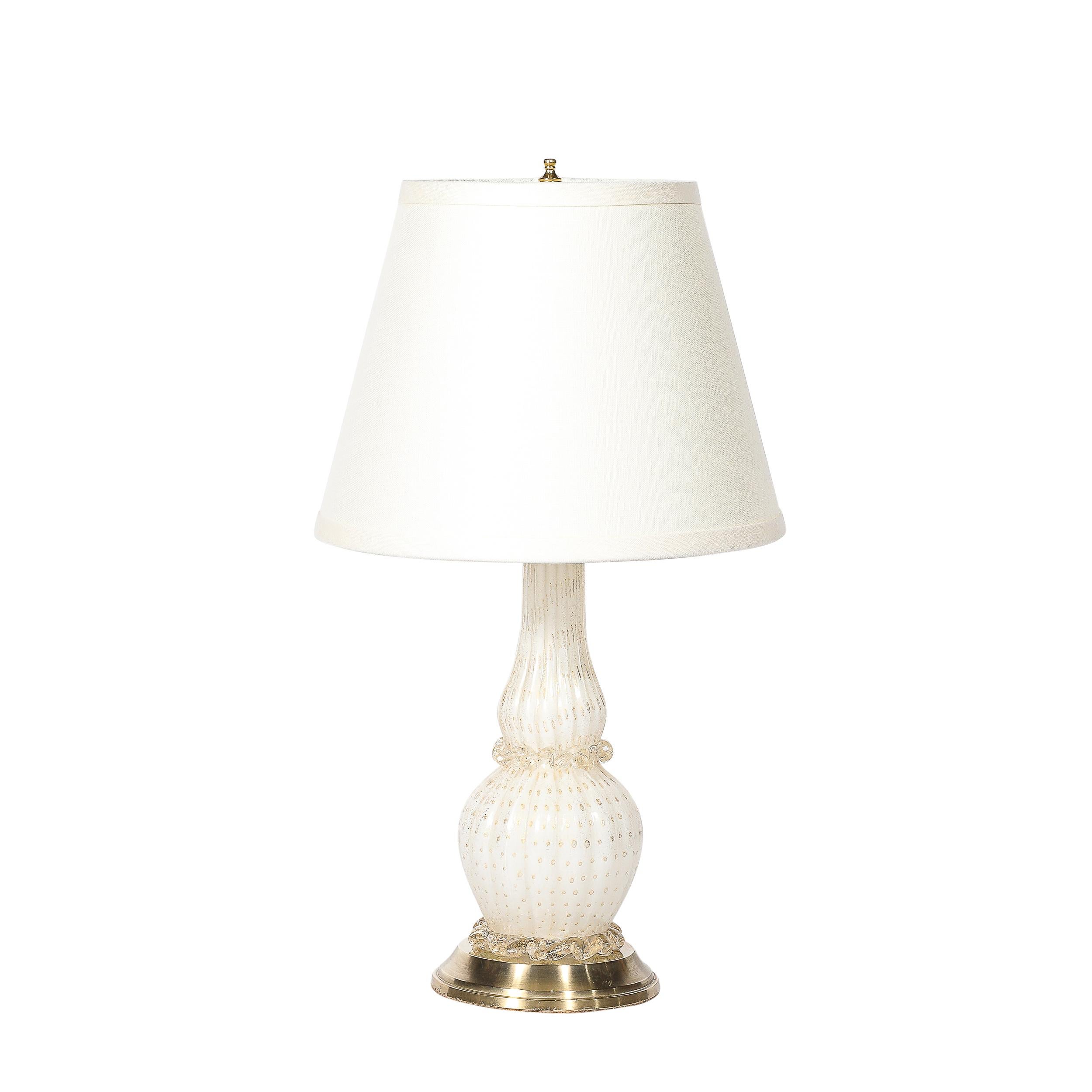 This delightful Pair of Mid-Century Modernist Hand-Blown Murano Glass Table Lamps in White W/24 Karat Gold Flecks and Brass Fittings originates from Italy, Circa 1950. Featuring a tiered geometric polished brass base on which the body of the lamps