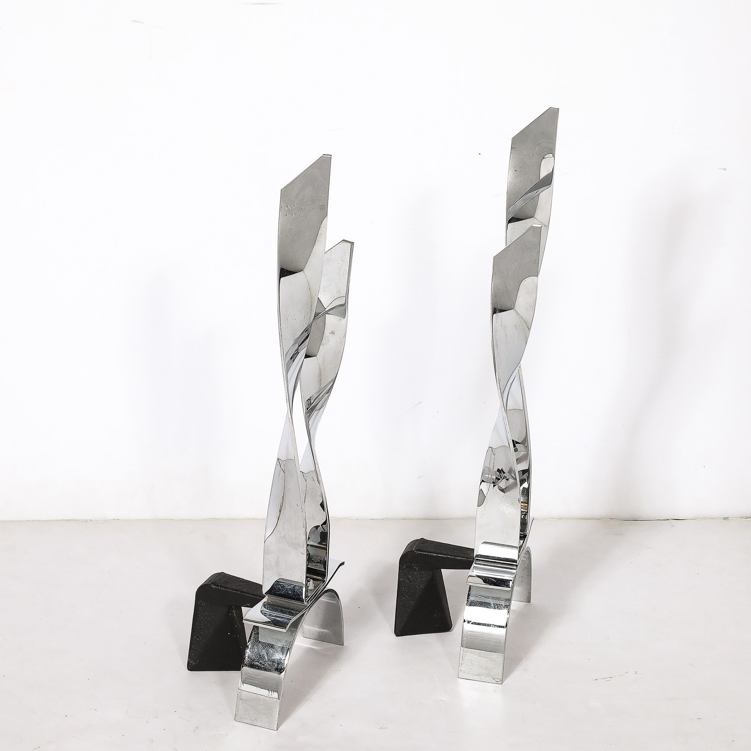 This bold and elegant Pair of Mid-Century Modernist Torqued Flame Andirons in Polished Chrome originate from the United States, Circa 1970. Features a dynamic minimal composition rendered in polished chrome bands, beautifully twisted to resemble