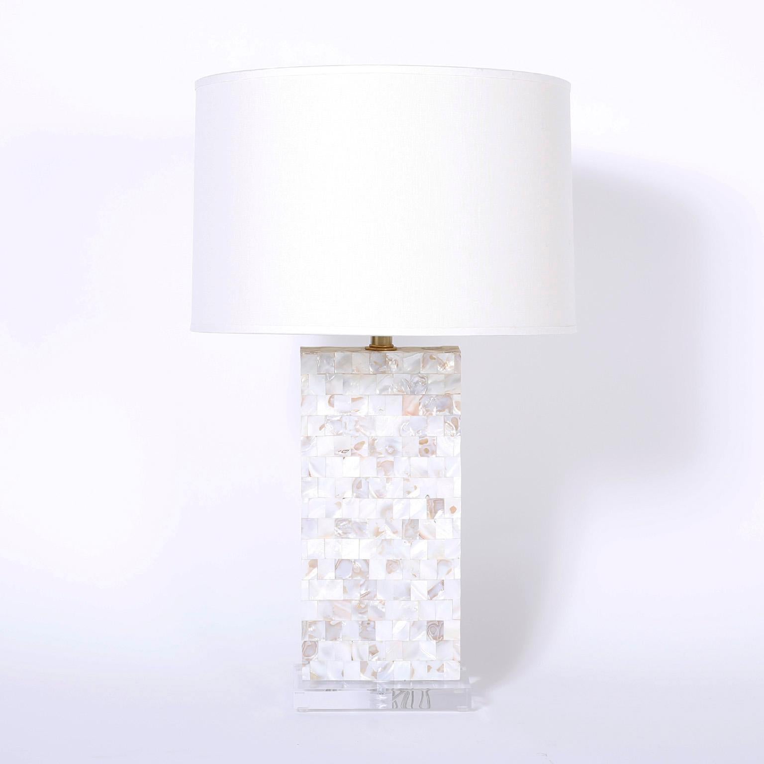 Pair of midcentury table lamps with a rectangular form featuring alluring mother of pearl mosaic bodies presented on Lucite bases.