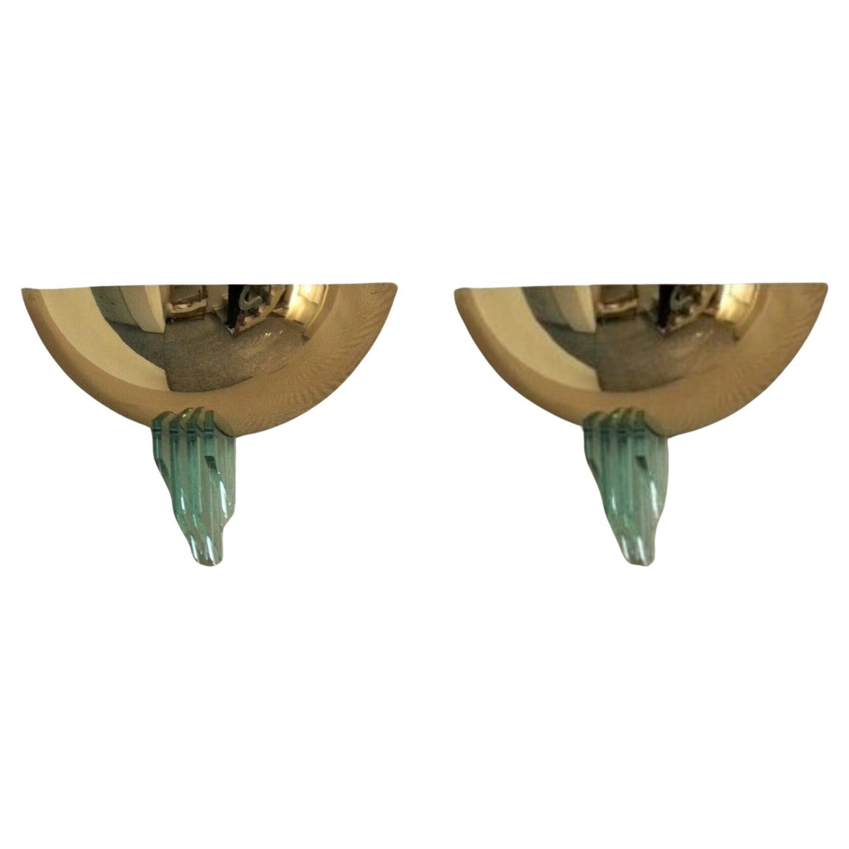 A Pair of brass and Murano glass wall lights in the Fontana Arte style, Italy, 1960s. Demi-cup shape decorate with four geometric profiles in thick polished glass on the base. Each sconce takes a E27 60watt screw bulb creating a warm, pleasant light