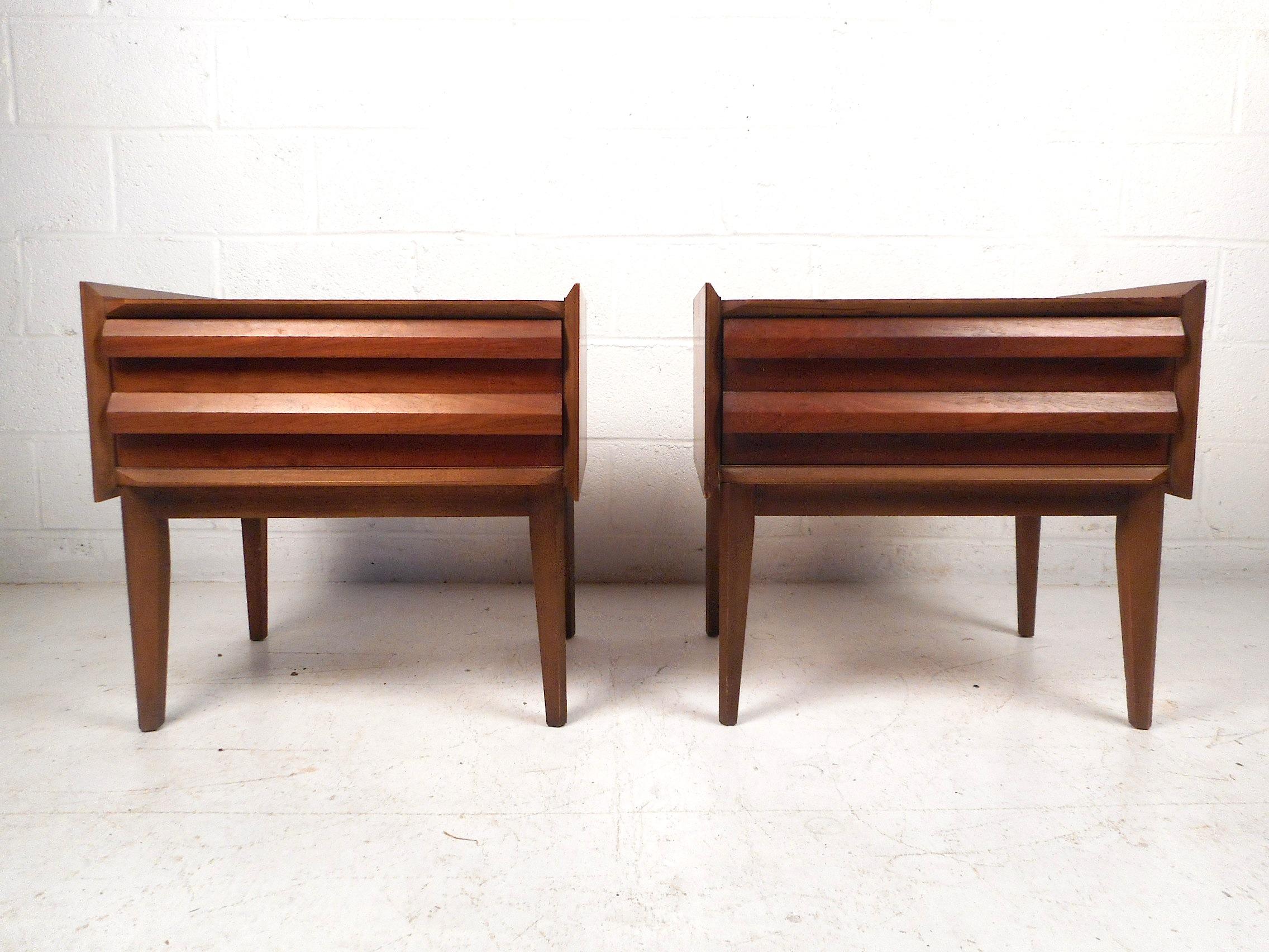 This unique pair of midcentury nightstands by Lane Furniture feature sturdy walnut construction, stylishly beveled wood siding on the tabletops, sculpted drawer pulls, and a single dovetail-jointed drawer which provides storage and signifies good