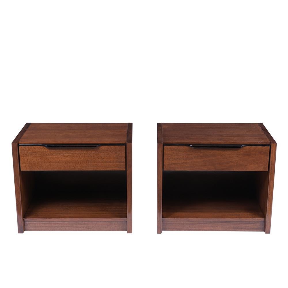 This pair of midcentury nightstands has been professionally restored and features a sleek design newly stained in a black and walnut color combination with a lacquered finish. The nightstands are made out of walnut wood, come with a large top drawer