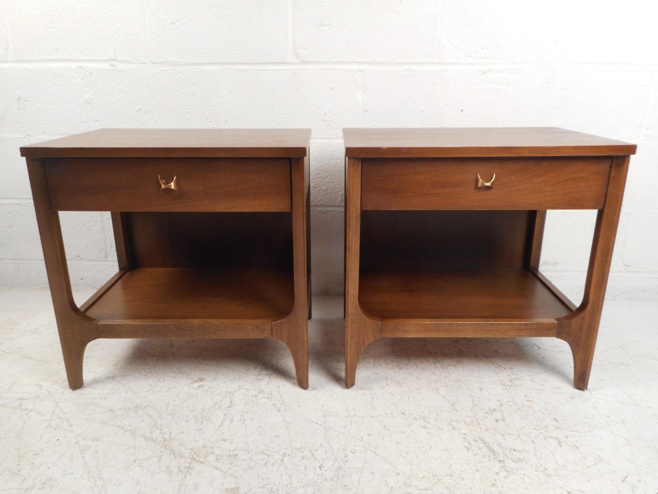Stylish pair of Mid-Century Modern nightstands or end tables manufactured by Broyhill. Signature brass drawer pulls open dovetail-jointed drawers, a shelf on the bottom of the tables offers additional storage space. Great midcentury pieces sure to