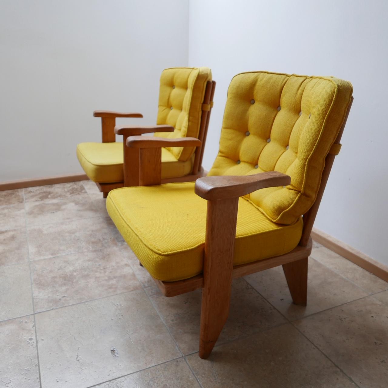 A pair of armchairs by French designers Guillerme et Chambron. 

French, circa 1960s. 

Solid oak, original upholstery that is usable but wants updating which we can arrange if needed. 

Retractable cupholders which are a useful but unusual