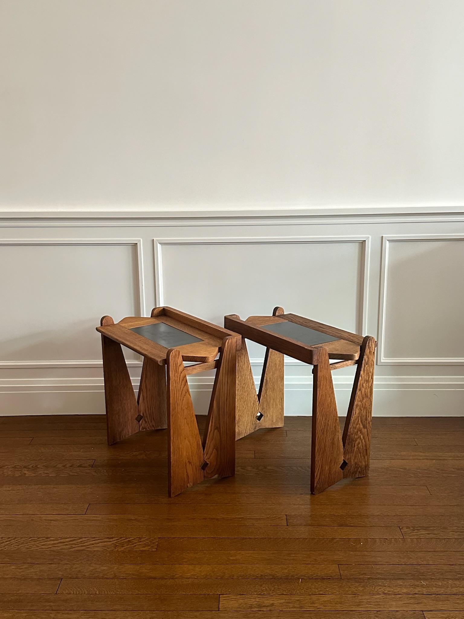 Pair of side tables by Robert Guillerme crafted from oak wood dating back to France in the 1960s with carved elements on the tops and sides.  In good condition with no major blemishes besides small chips in the wood on the top.